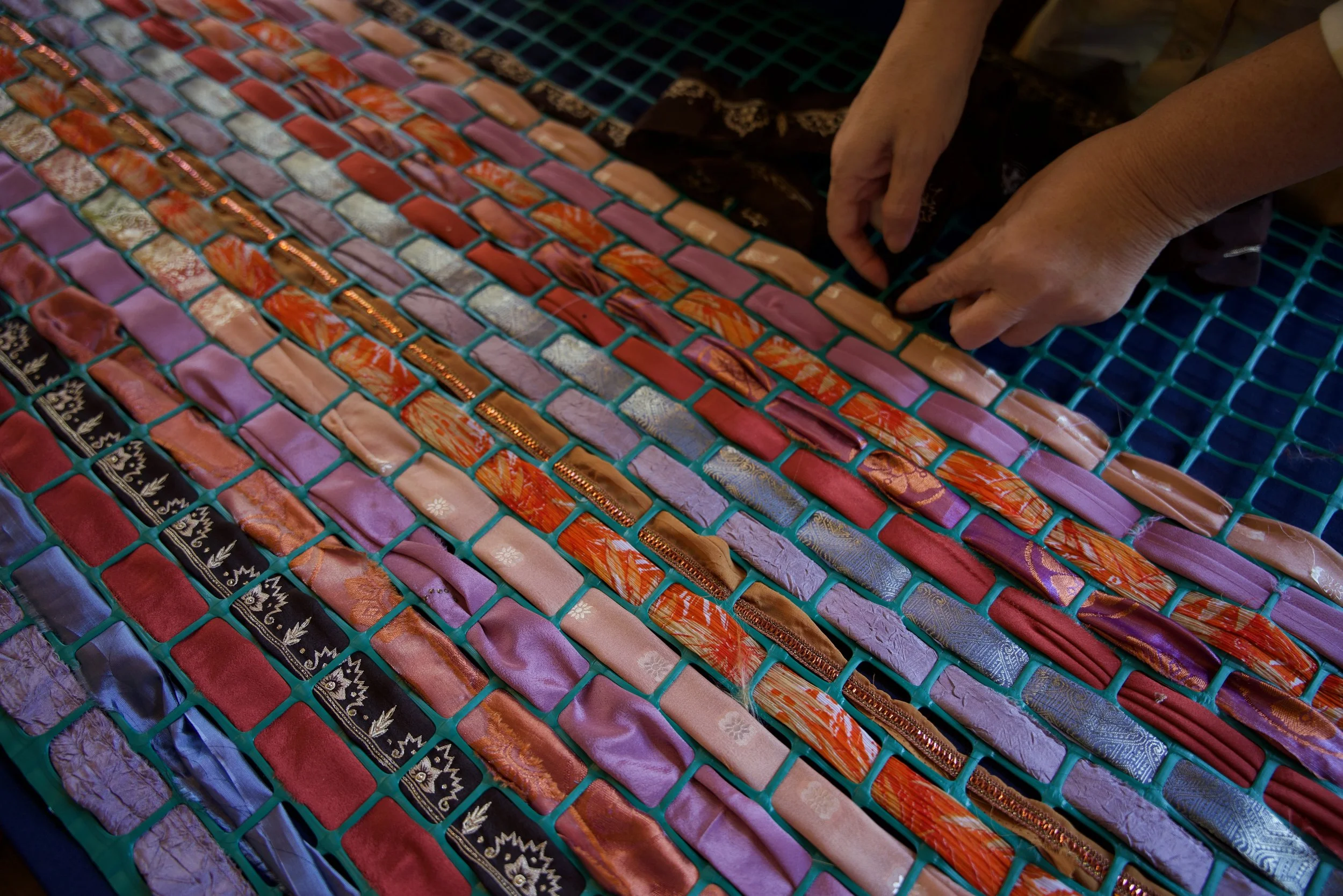 Hands weaving multicolored fabric
