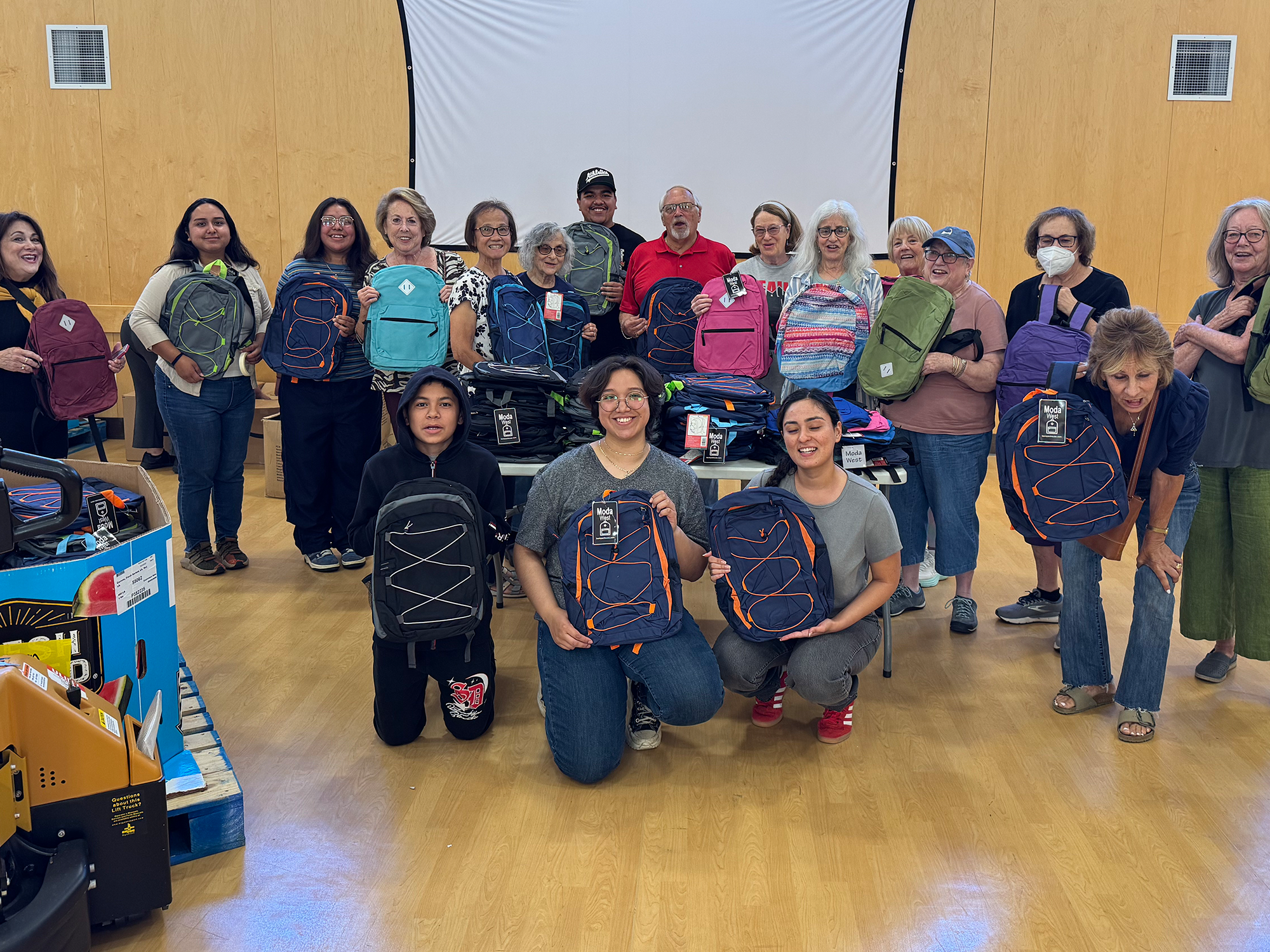 A group of people smiling while holding backpacks