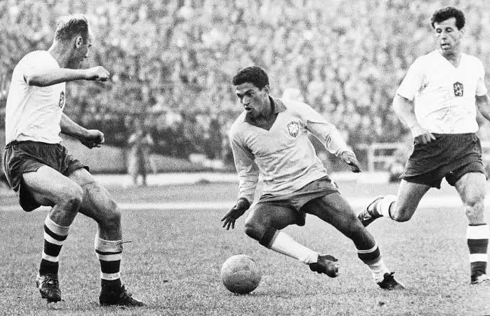 Garrincha carrying ball past defender in black and white