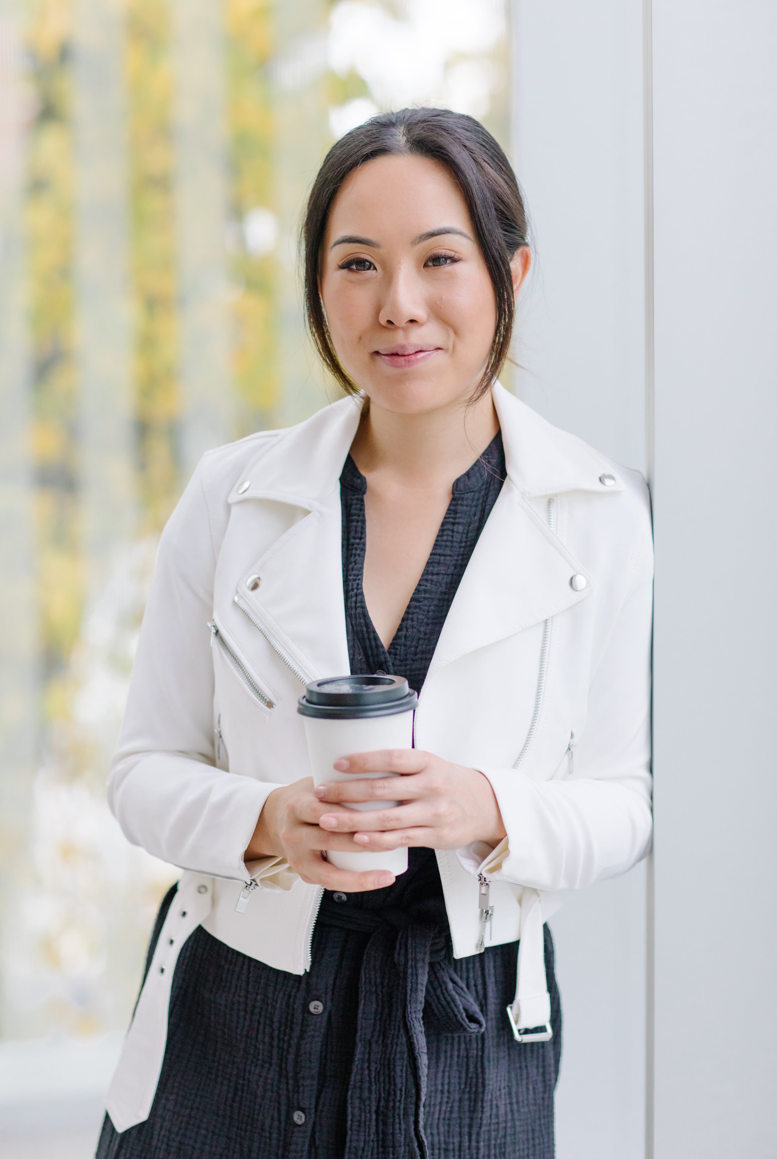 Woman in a white jacket holding a coffee cup