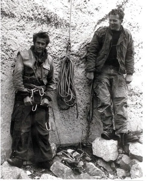 22. Black-and-white photograph of two climbers resting at the base of a rock face with ropes and hardware laid out.jpg