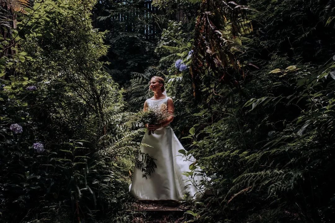 Straight out of a fairy tale. Beautiful bride Malea stepping through the lush greenery @theblackbarnlaketarawera 🤍