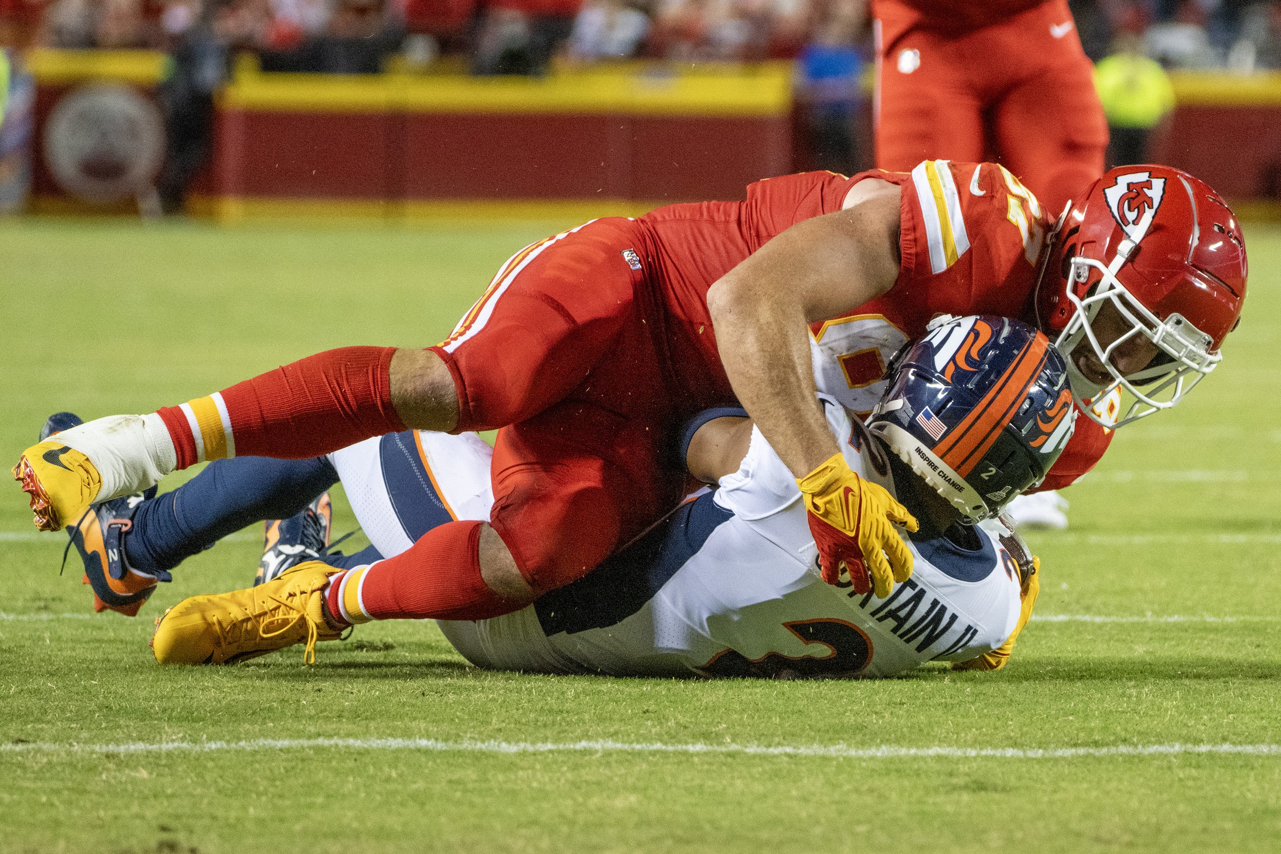  Kansas City Chiefs tight end Travis Kelce (87) tackles Denver Broncos cornerback Pat Surtain II (2) in the second quarter during an NFL football game against at GEHA Field at Arrowhead Stadium on Thursday, Oct. 12, 2023, in Kansas City.  