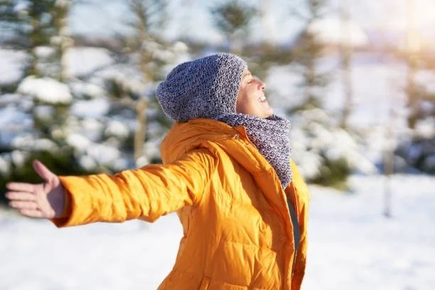 A woman in the winter of menopause embracing the sun and the beginning of a new seasons.