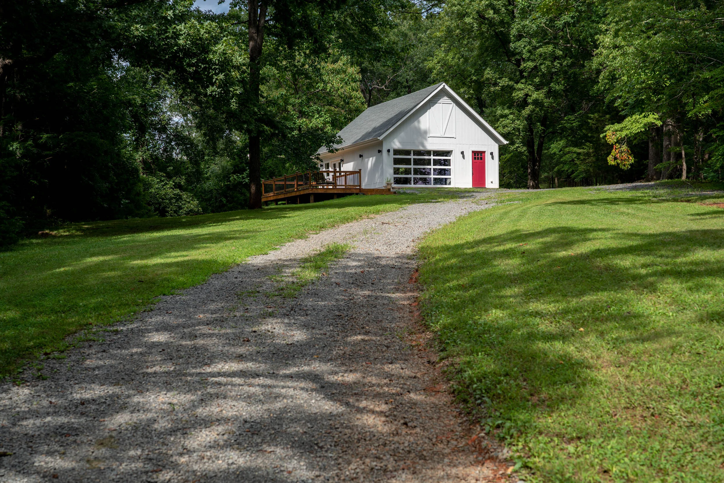 The First Lady's Food Lab from the bottom of the entry driveway, the structure is white with a red entry door and white window framed garage door.