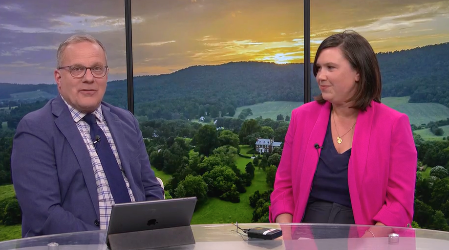 Rebecca Deeds, right, sits with 29 News Anchor in front of a backdrop screen of Morven. 