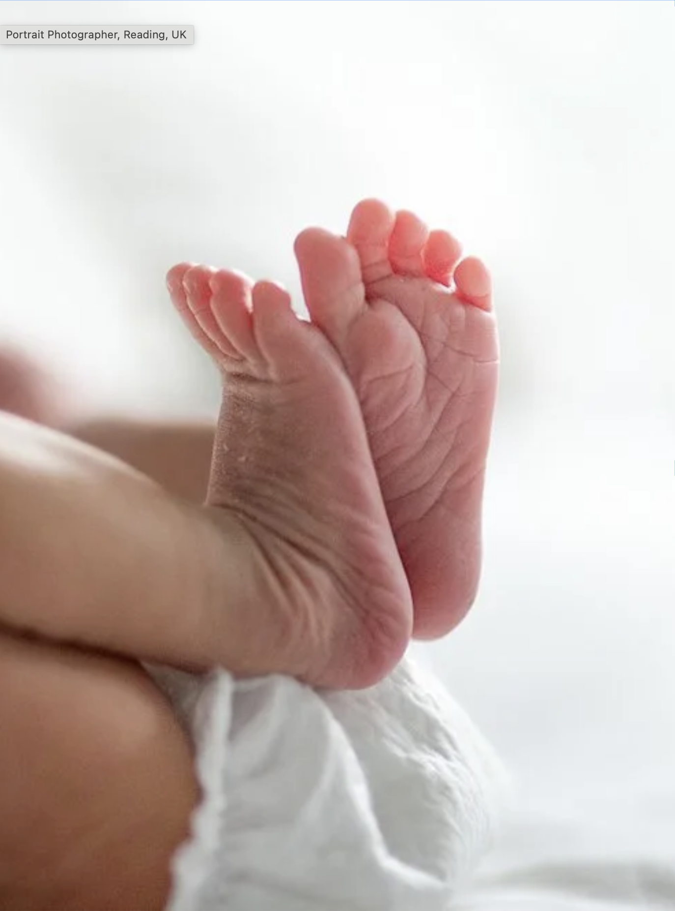 Close-up of a tiny newborn baby's hand being held by an adult hand.