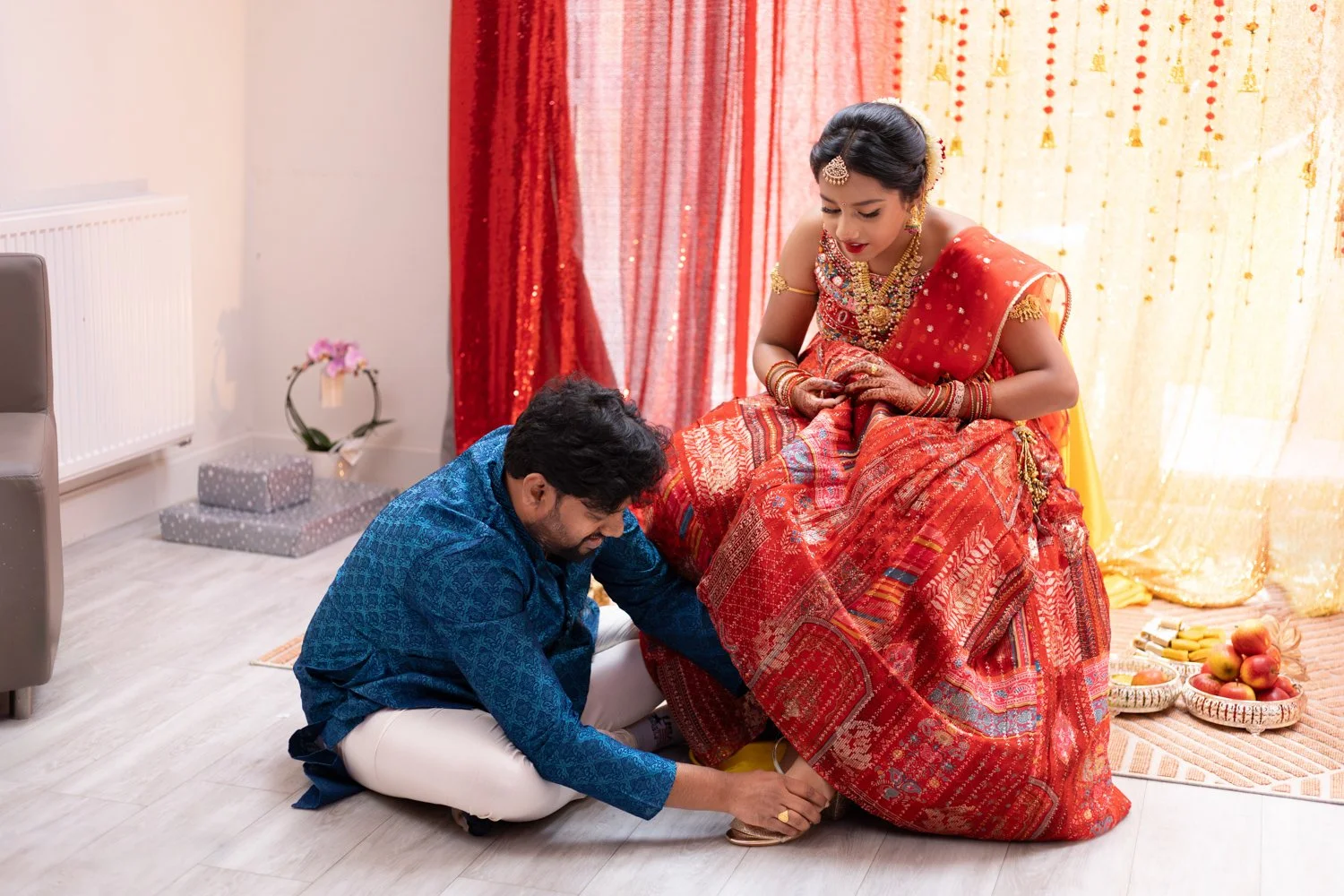 A girl in traditional attire and her dad helping her get ready during a colourful half saree ceremony captured by event photographer basingstoke