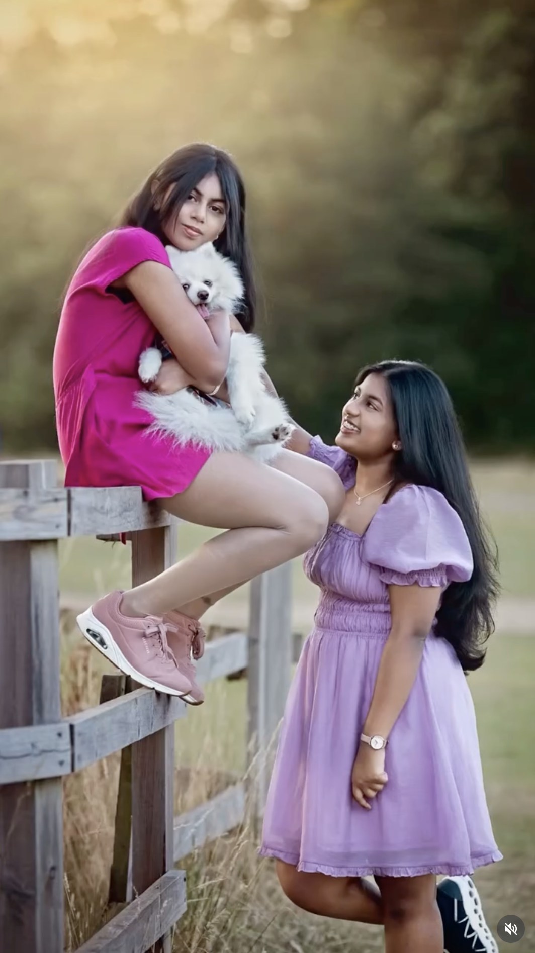 Two girls in pink and purple dresses laughing together outdoors, captured during a outdoor portrait session in Berkshire.