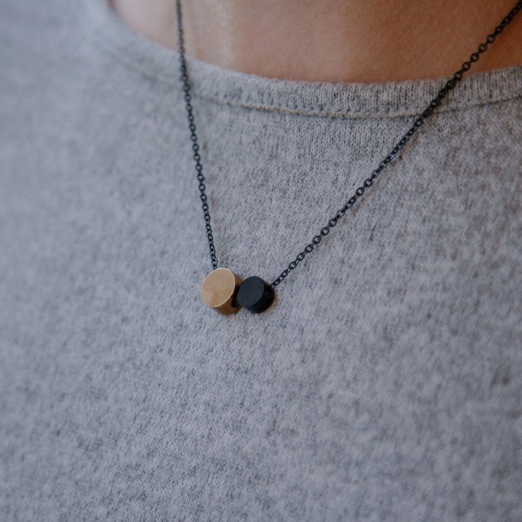 Two-tone pendant necklace on gray shirt