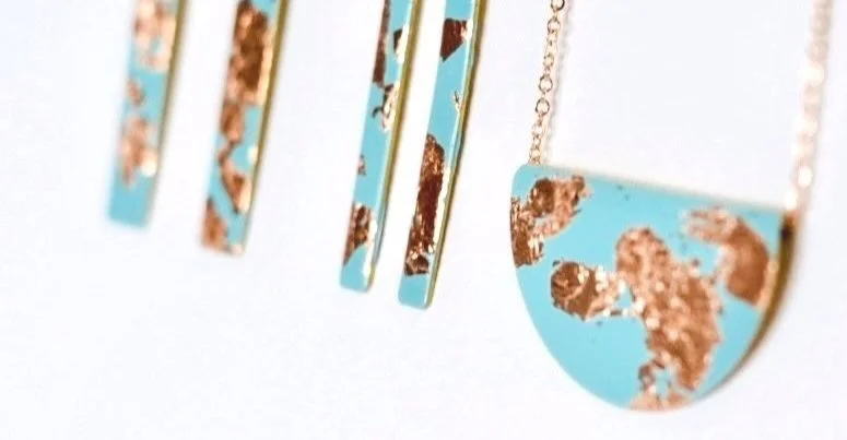 Gold and turquoise abstract jewelry pieces against a light background
