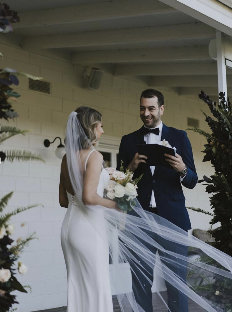 Bride and Groom stand at the altar of The Farm Yarra Valley between two flower towers made by Petal and Sage
