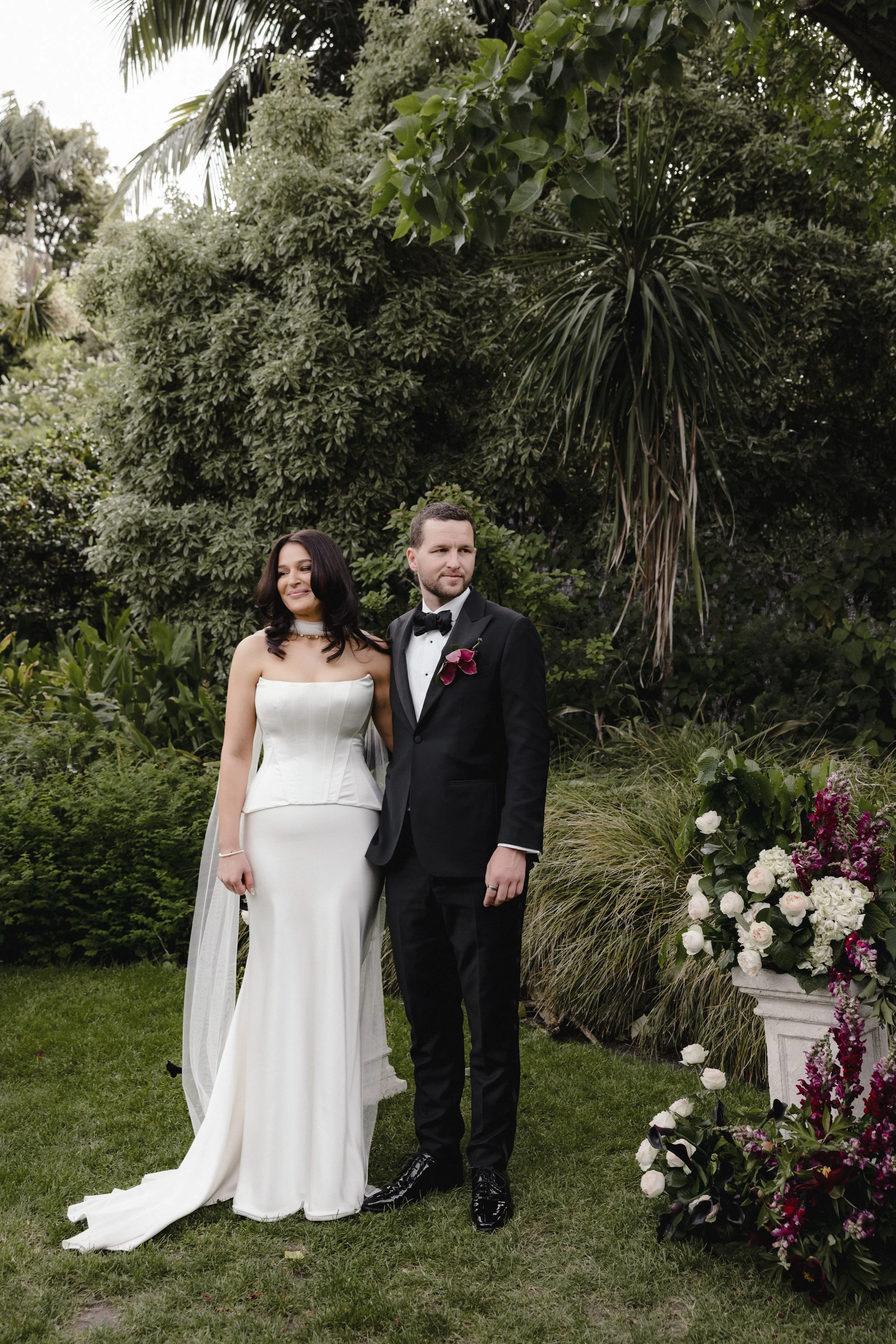 Newly weds husband and wife stand at the altar at Gardens House in the Botanical Gardens surrounded by flowers made by Petal and Sage