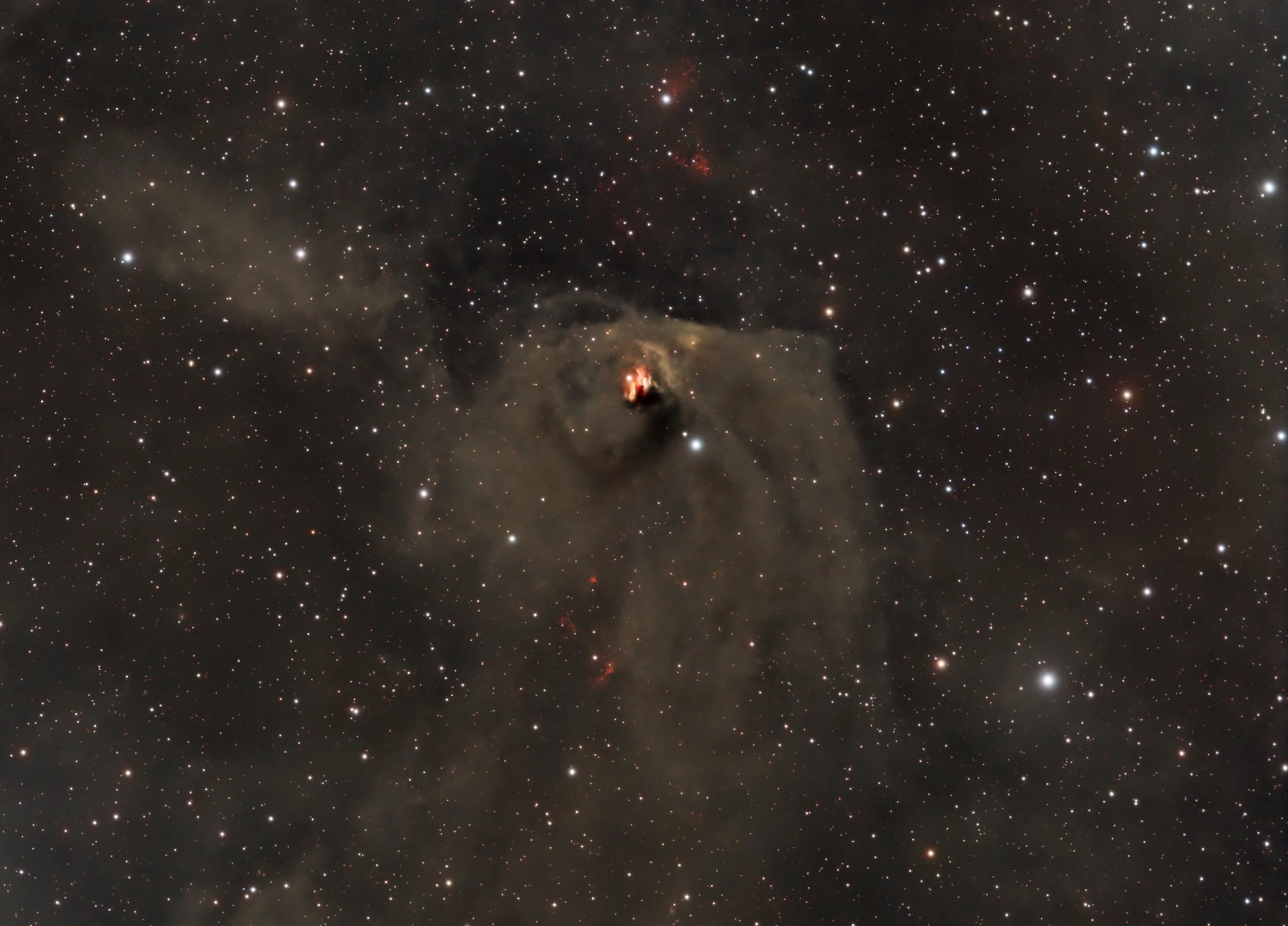 Hind’s Variable Nebula NGC 1555 glowing near the Hyades in Taurus, showing a bluish reflection fan around T Tauri against a rich star field.