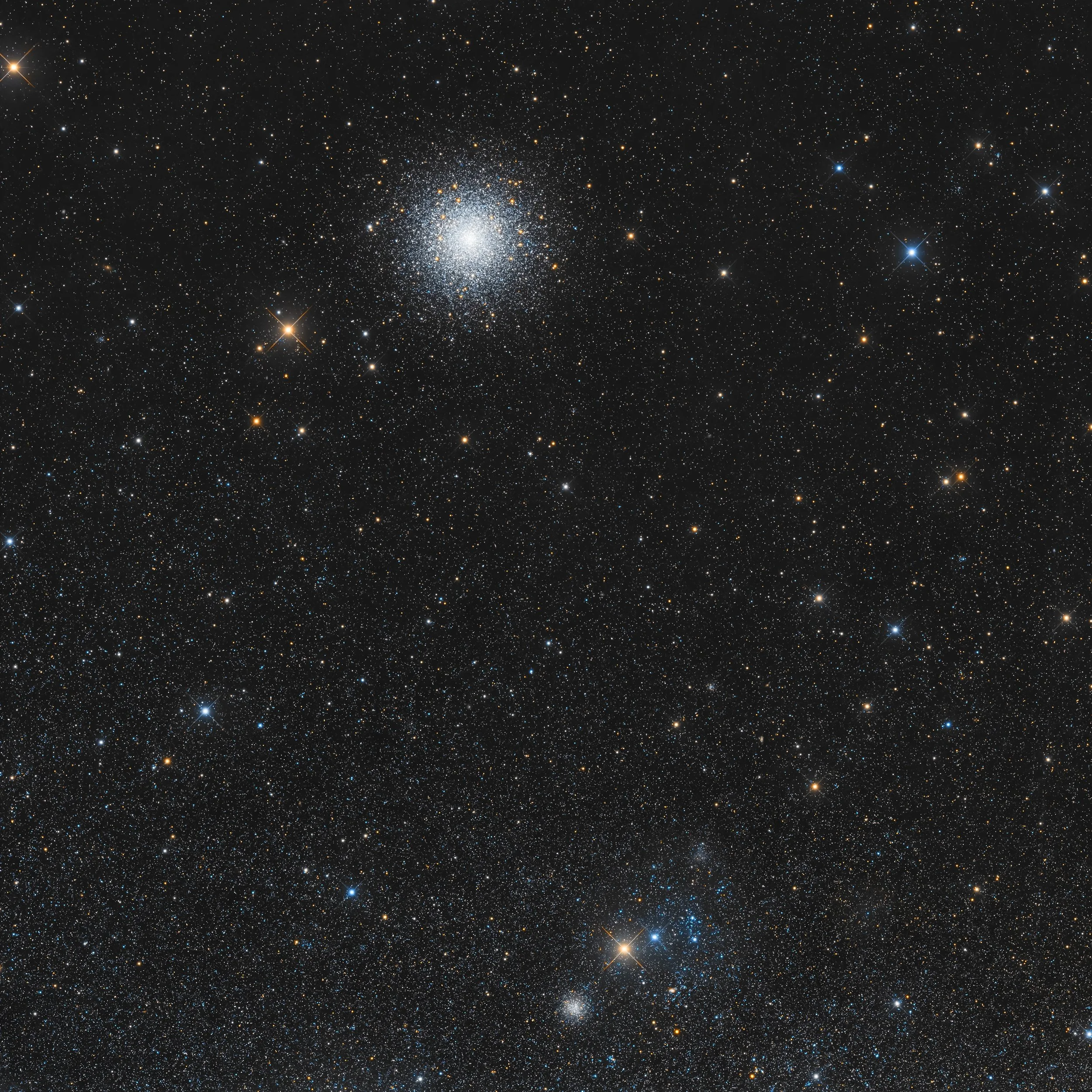 A dense globular star cluster surrounded by a rich star field, with bright stars arranged in a pattern resembling a Christmas tree topped by a glowing stellar star.