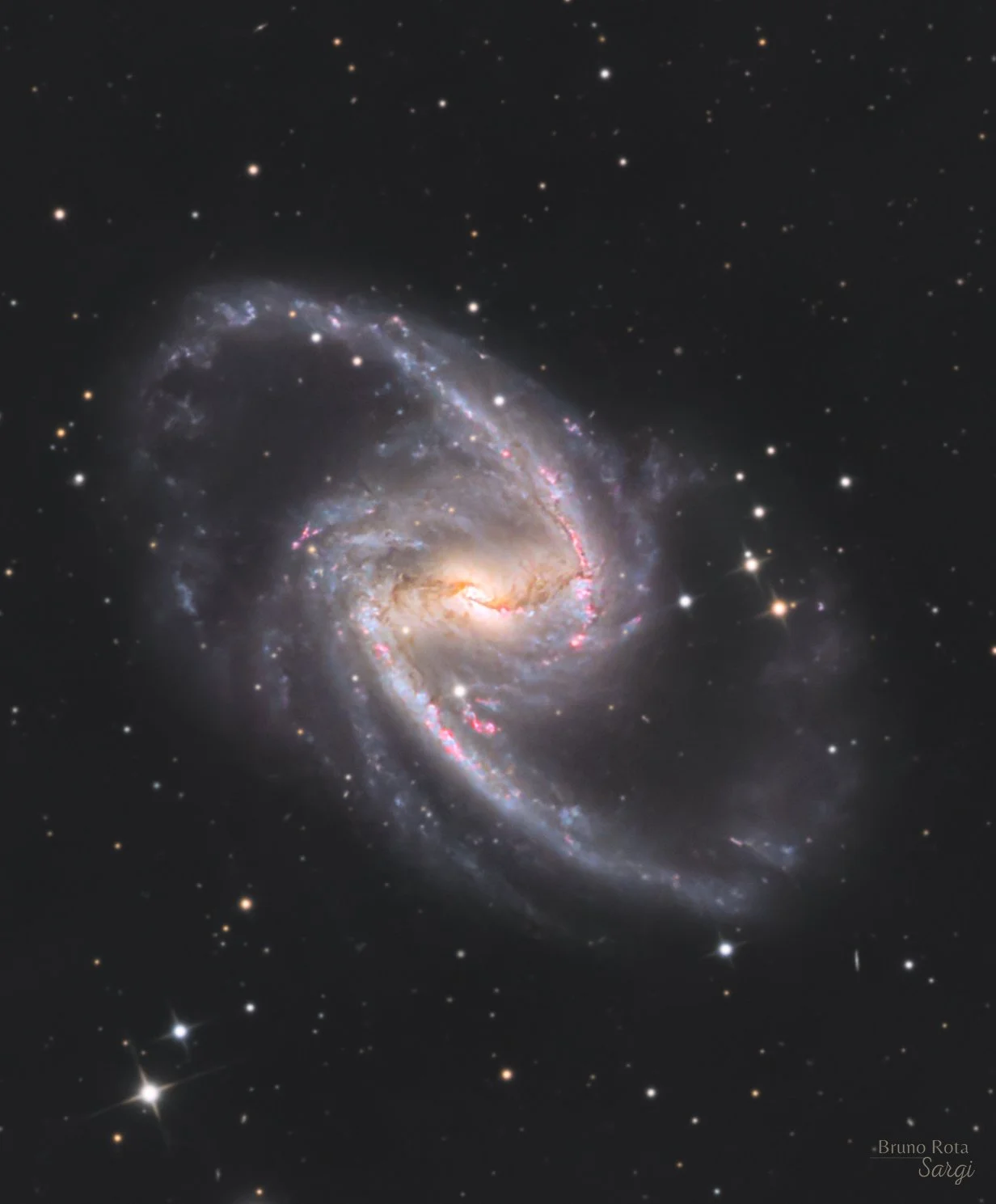 NGC 1365, a large barred spiral galaxy with a bright core, sweeping arms, and pink star-forming regions, surrounded by a field of foreground stars and distant galaxies.