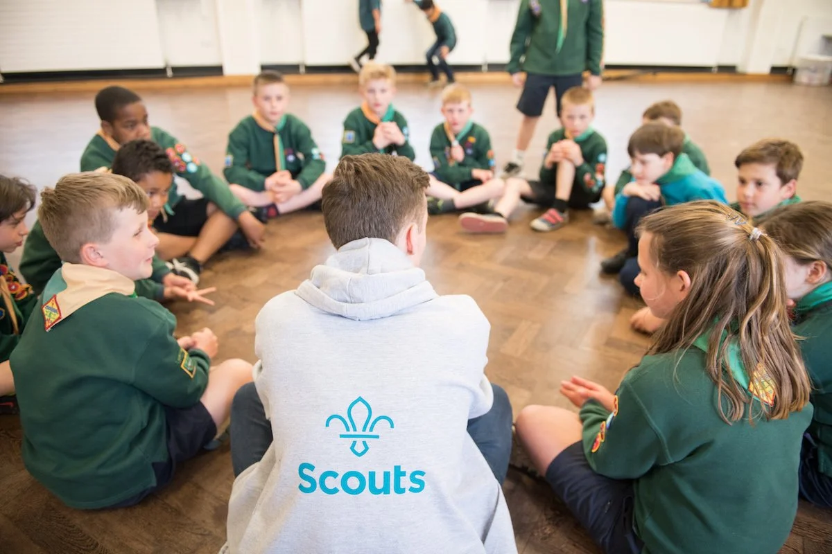 Group of young scouts sitting in a circle indoors