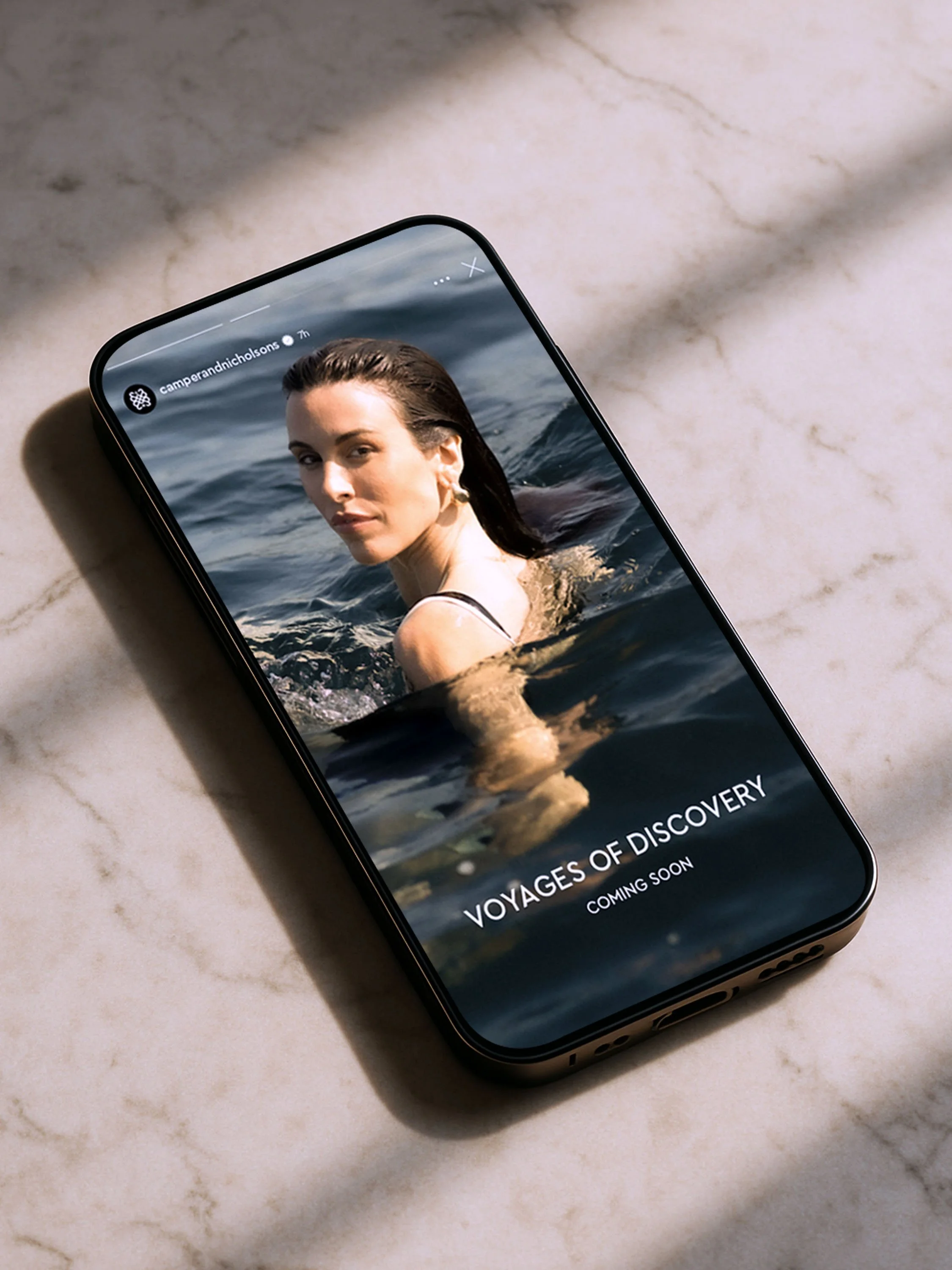 Image of an phone on a marble table. The phone shows a C&N social media story of one of their campaigns