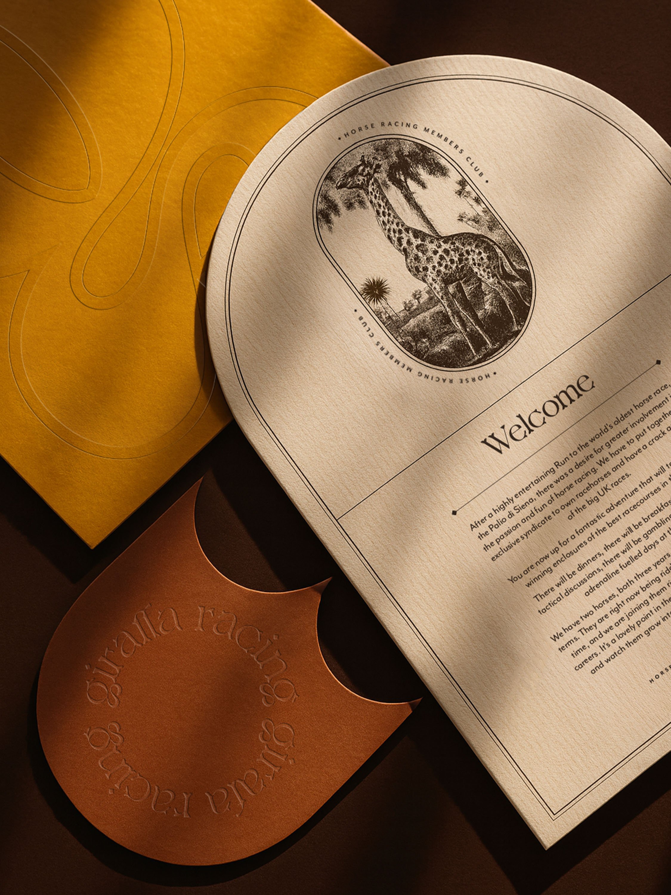 A collection of an invite and other stationery cards, with embossed finishes and illustrative emblems. Colours are warm ochres, dark oranges and deep browns