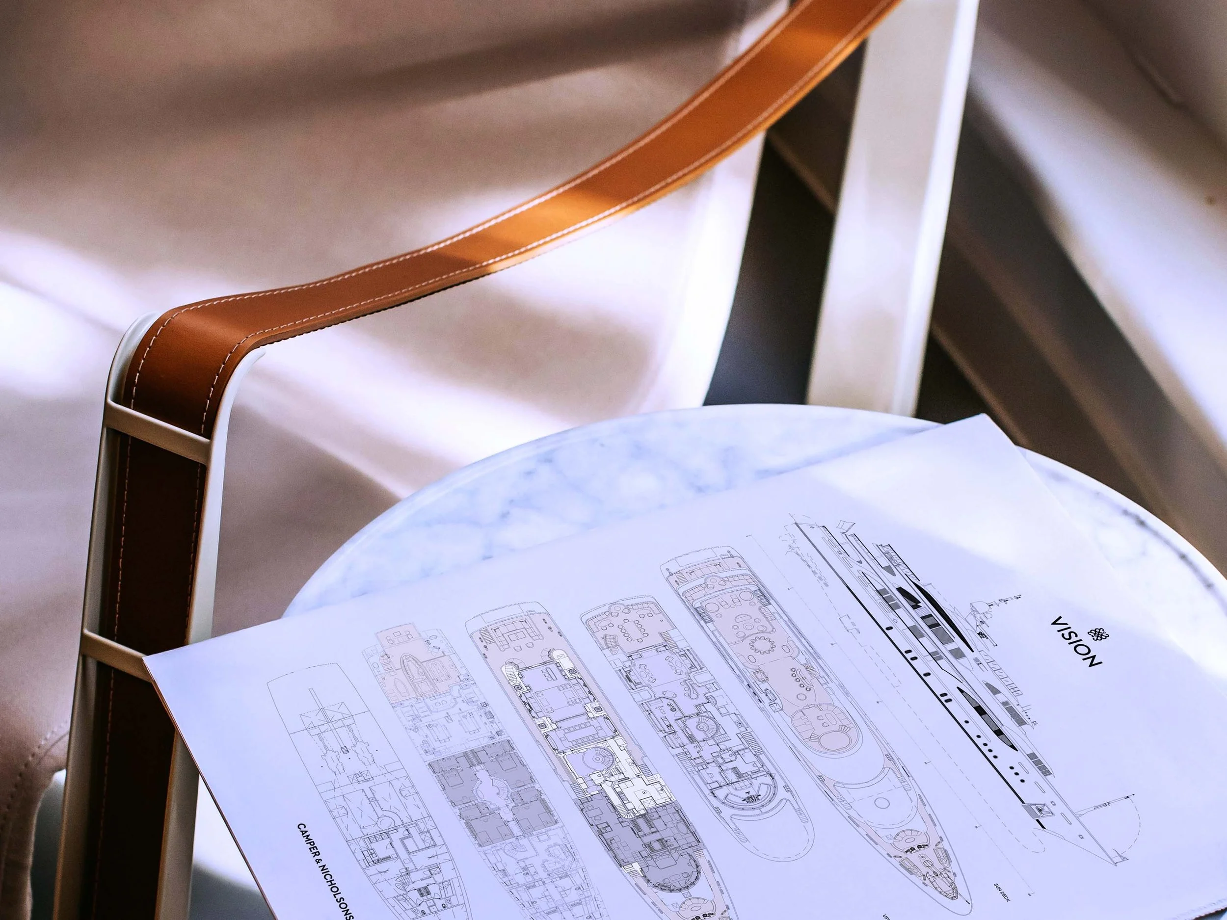 Image of a chair and a table with a book, showing branded yacht plans