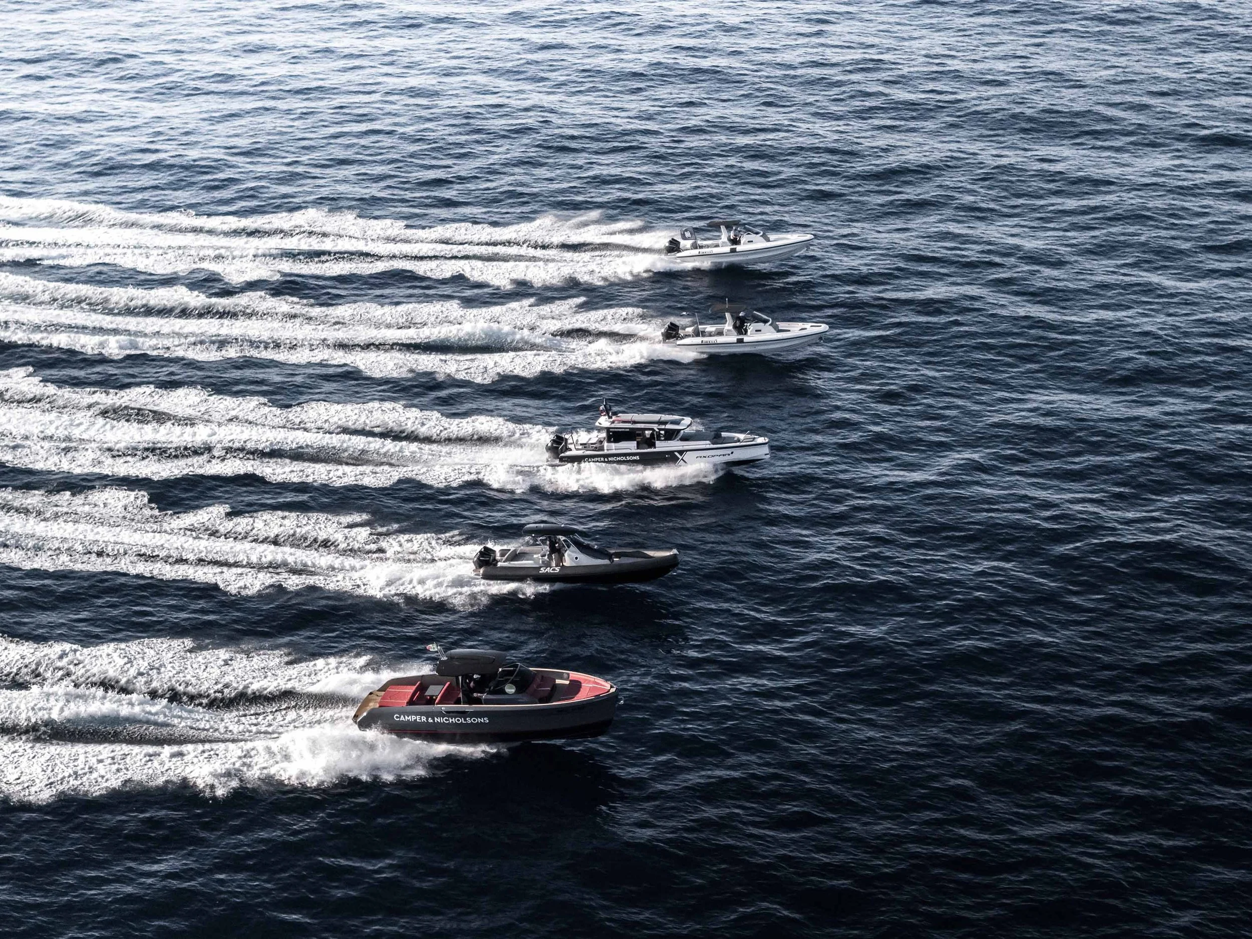 Image of four speedboats aligned, speeding at sea. The boats have the Camper & Nicholsons logotype printed on them