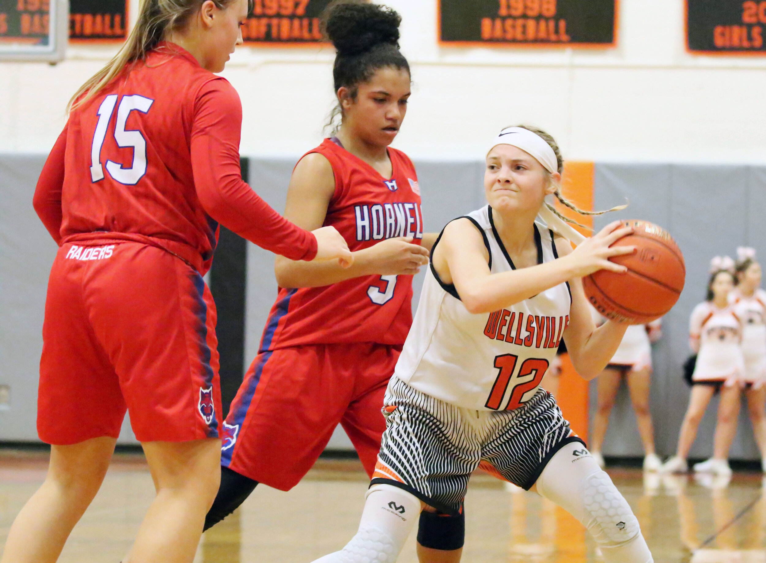  Wellsville sophomore Emily Costello (12) looks to make a pass inside against pressure applied by Hornell during Friday’s home contest. [Chris Brooks/WellsvilleSports.com] 