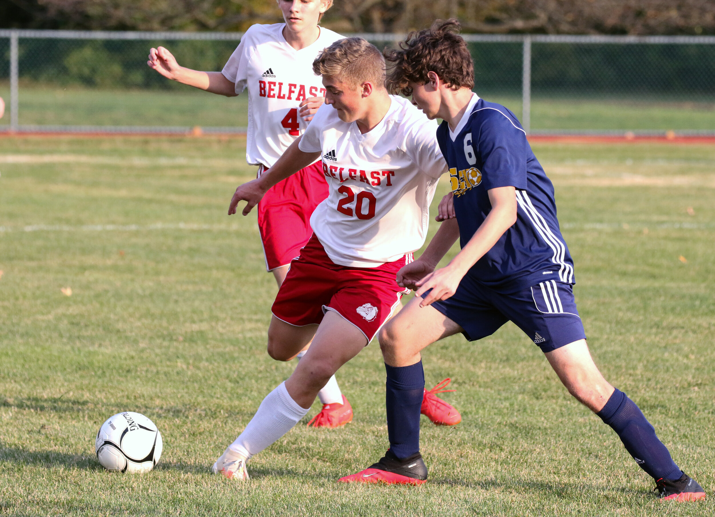  Belfast junior Matt Weaver (20) looks to clear the zone while under pressure from the defense of Scio  sophomore Jordan White (6) during Saturday evening’s contest in Scio. [Chris Brooks/WellsvilleSports.com] 