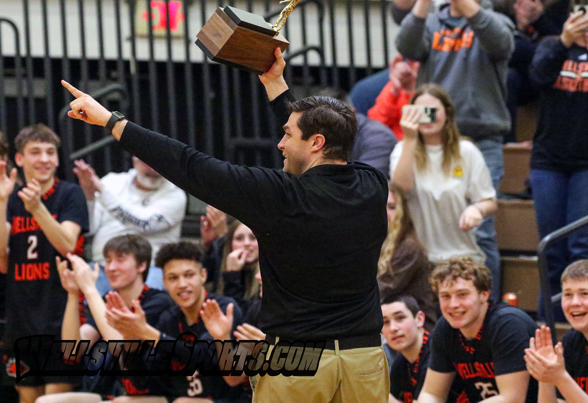 Wellsville head coach Raymie Auman points to the student section while hoisting the Class B2 Championship brick high in the air after defeating Mynderse by a 66-58 count to claim their third title in the last seven years, in Webster. [Chris Brooks/W