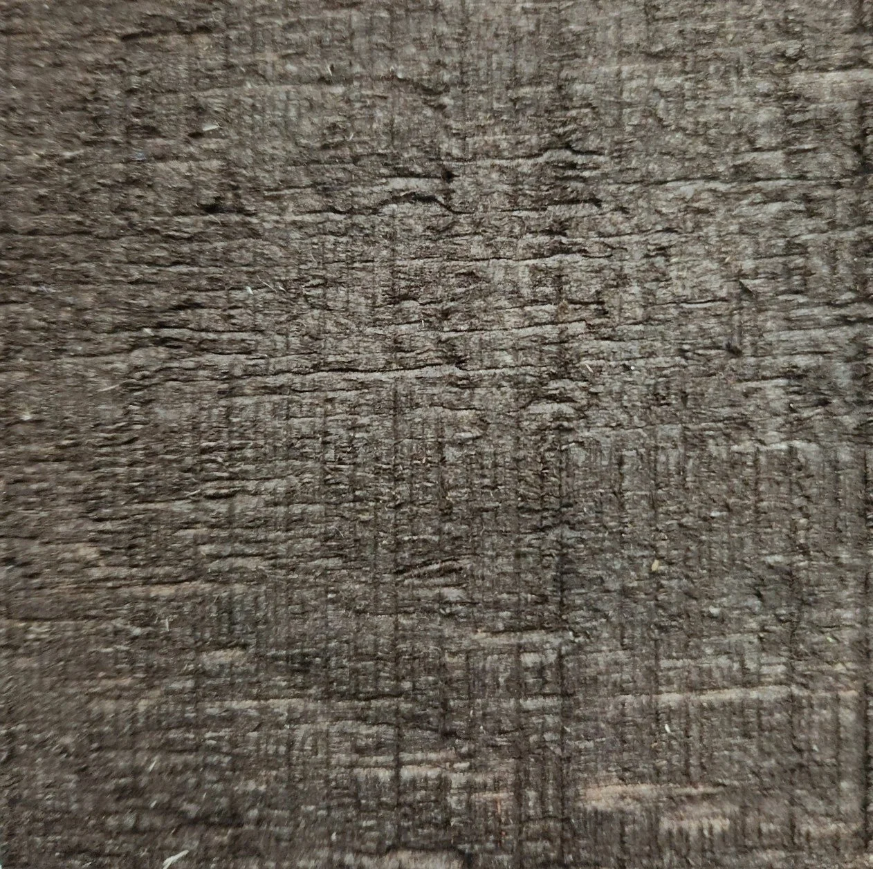 Close-up of a weathered, brown wooden surface with visible grain and texture.