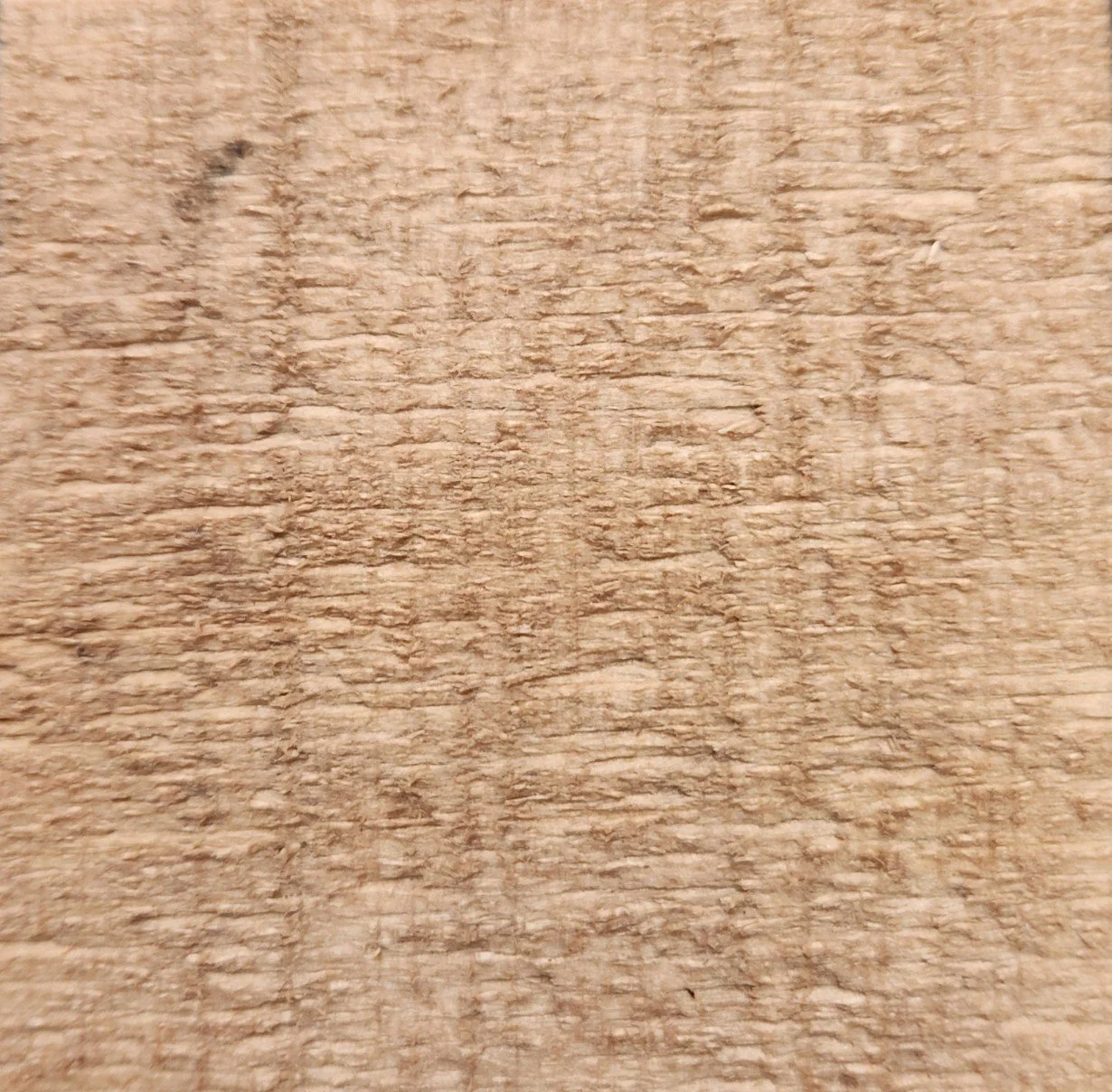 Close-up of a textured wooden surface with natural grain and light brown color.