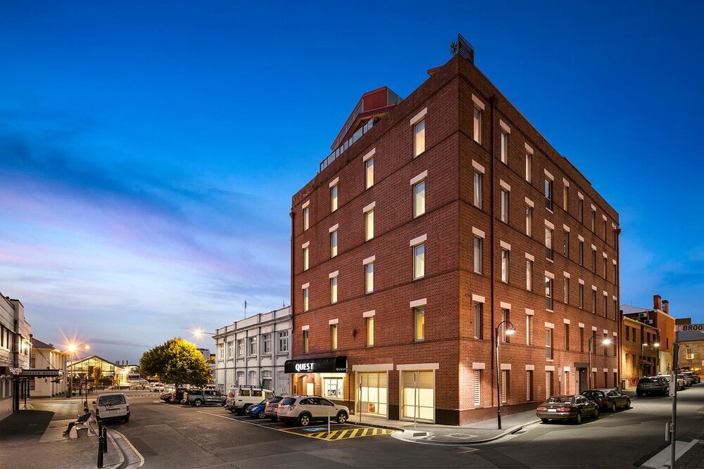 Brick hotel building at dusk with cars parked on the street