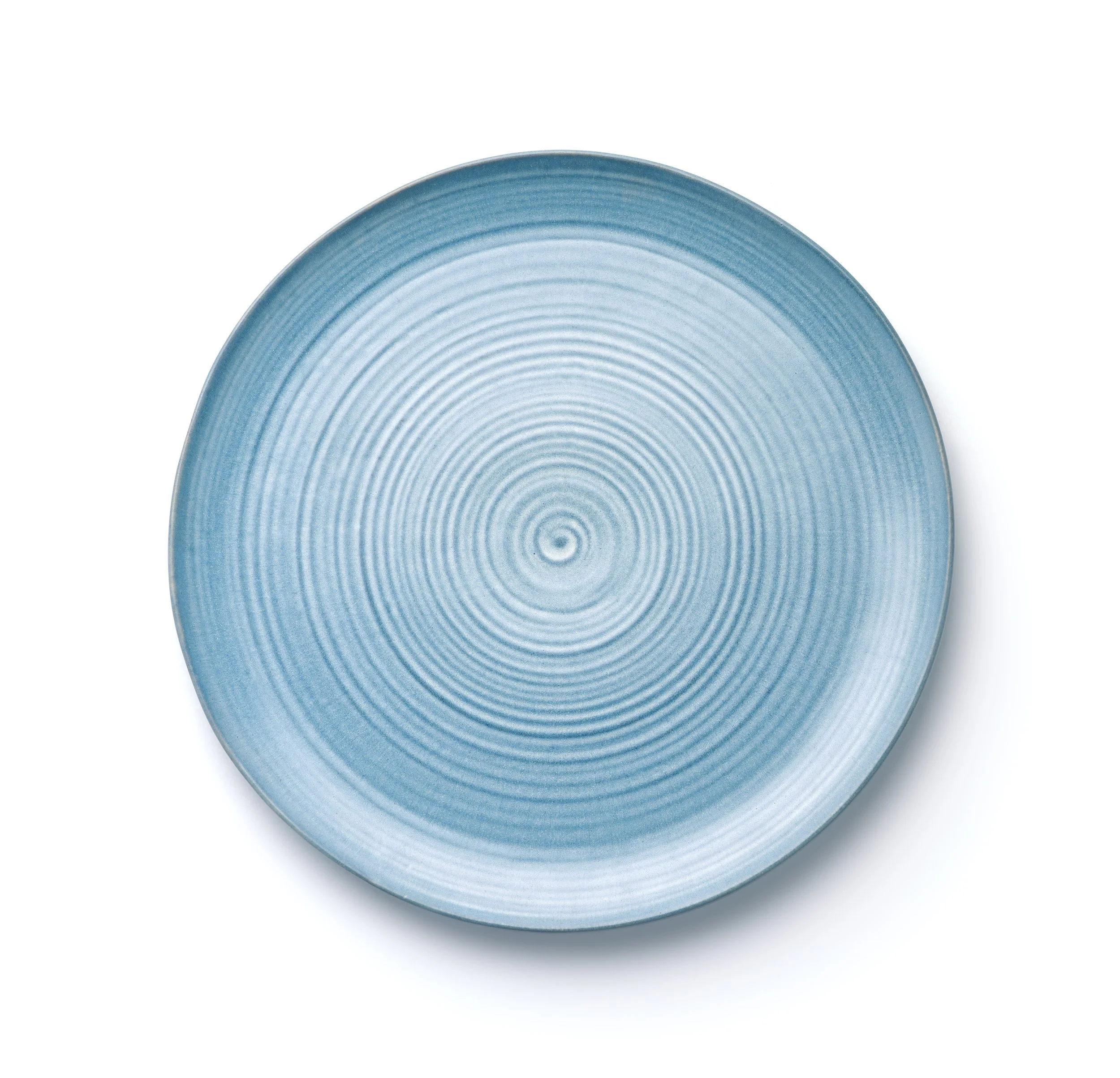 Close-up of a blue ceramic plate with concentric circular ridges, viewed from above on a white background.