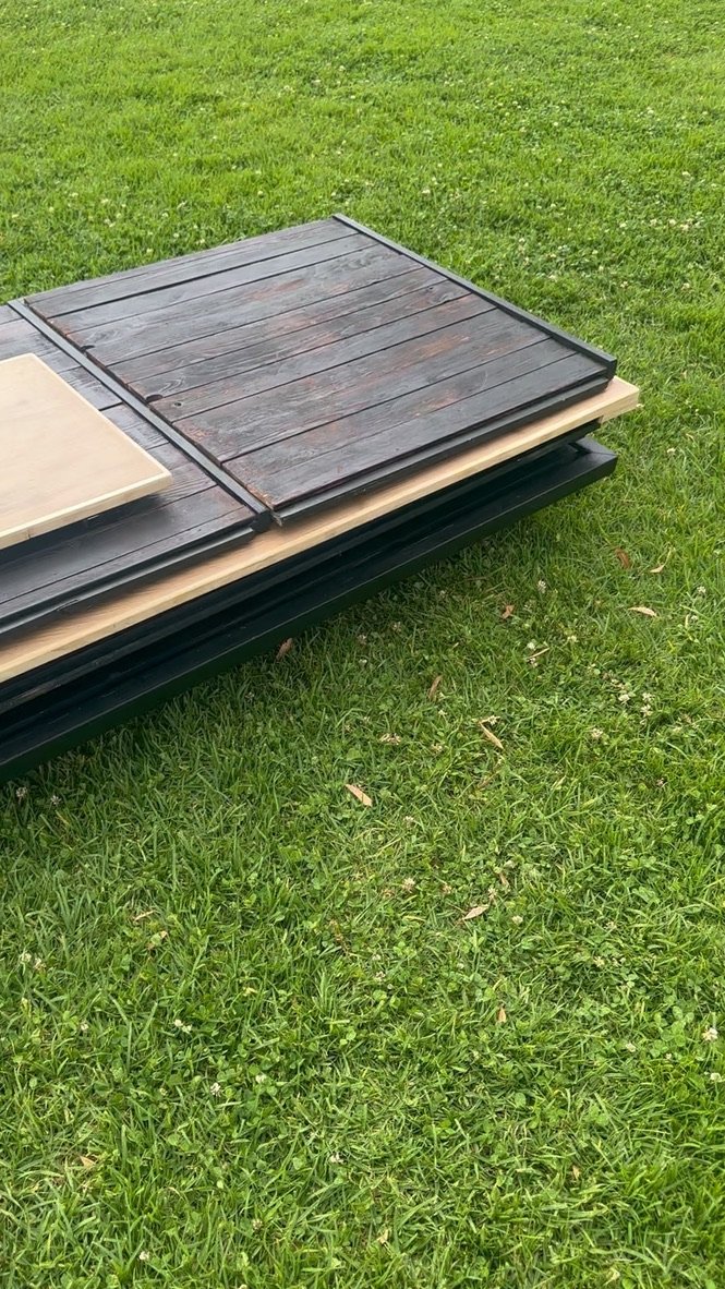 A stack of different types of outdoor decking materials placed on grass.