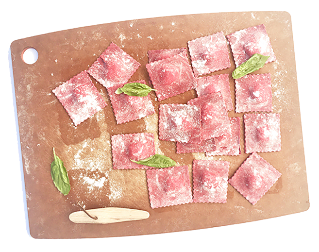 Uncooked square ravioli pasta with pink filling, garnished with basil leaves, on a wooden cutting board sprinkled with flour.