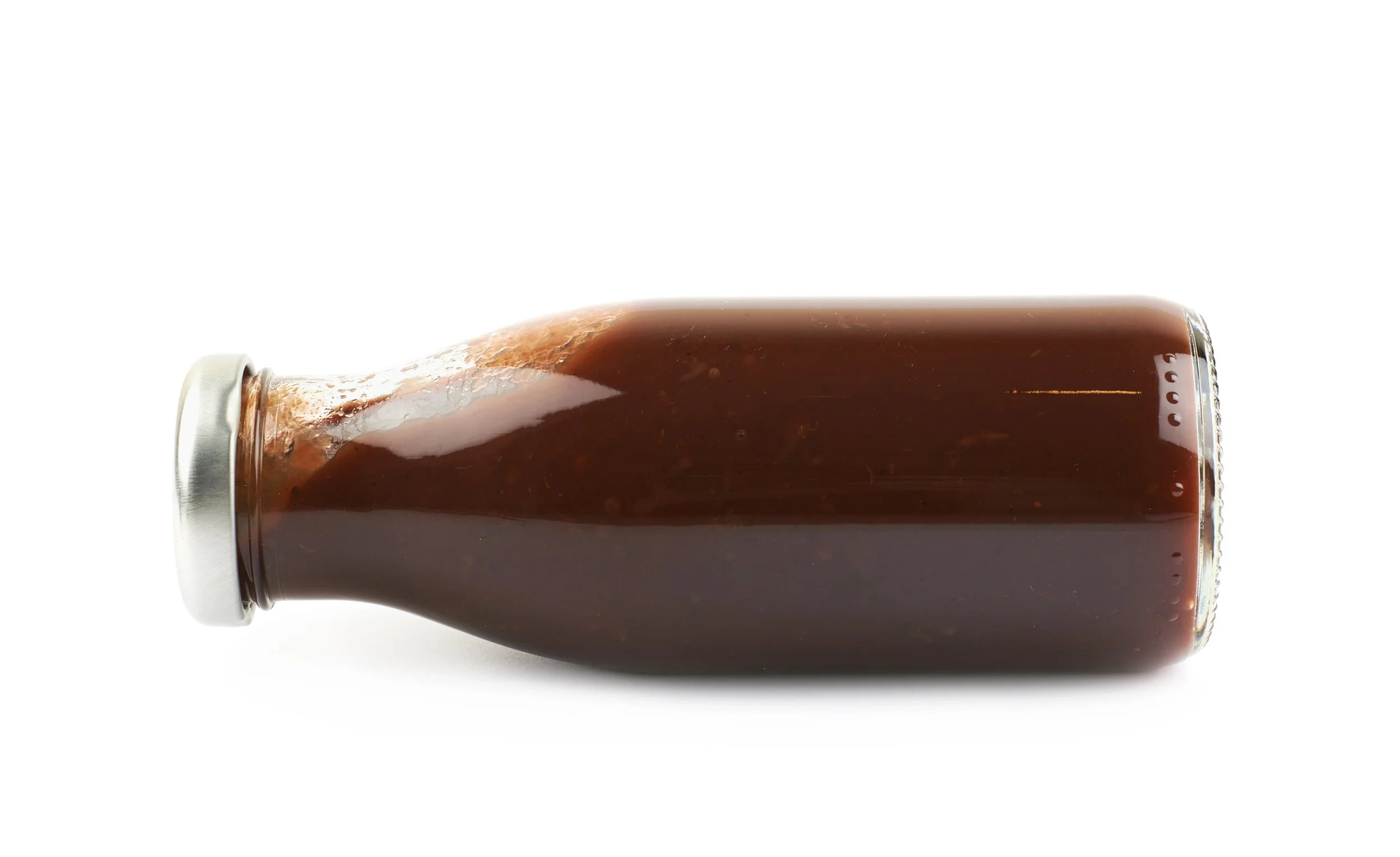 A glass soda bottle lying on its side against a white background.