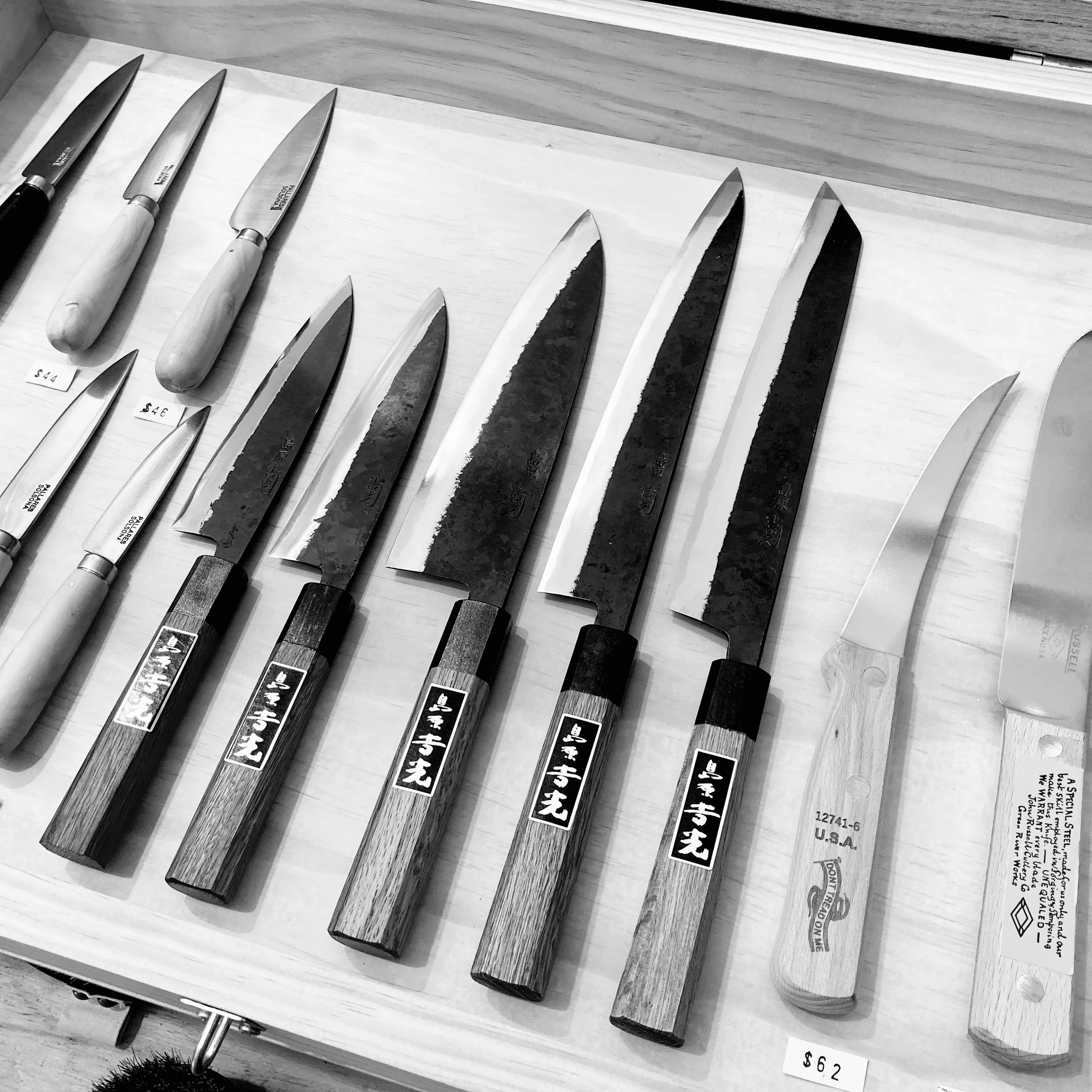 Japanese knives displayed in glass cabinet.
