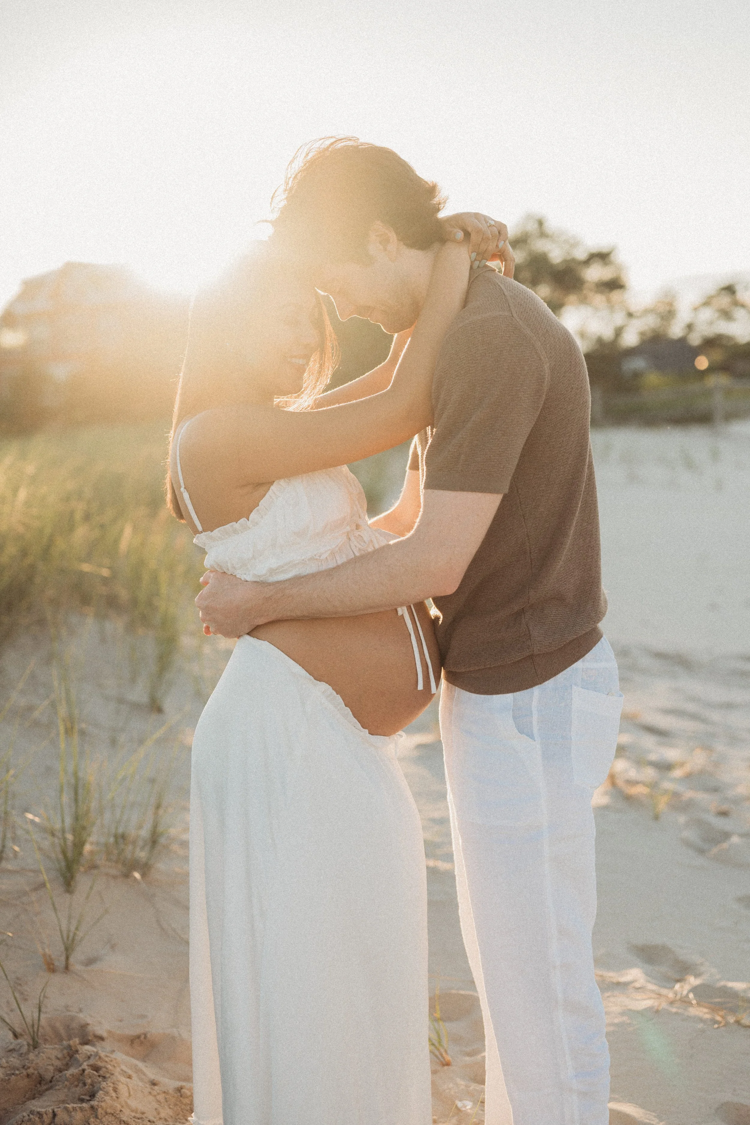  Couple posing for a maternity photo on the beach in Maine 