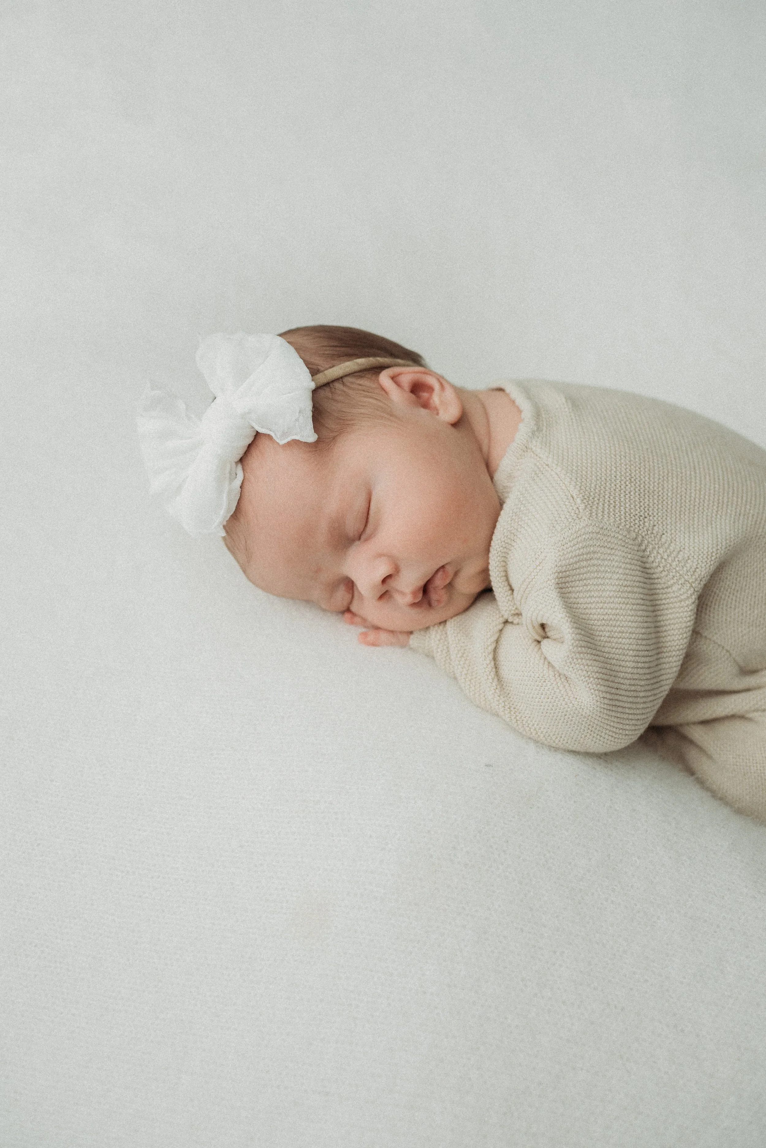Baby girl laying on hands in newborn Session