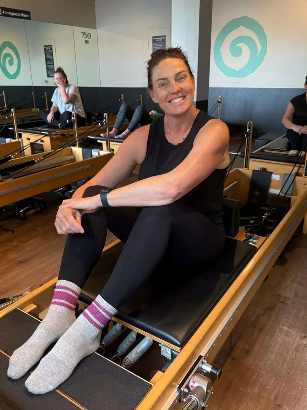 Person sitting on a pilates reformer smiling
