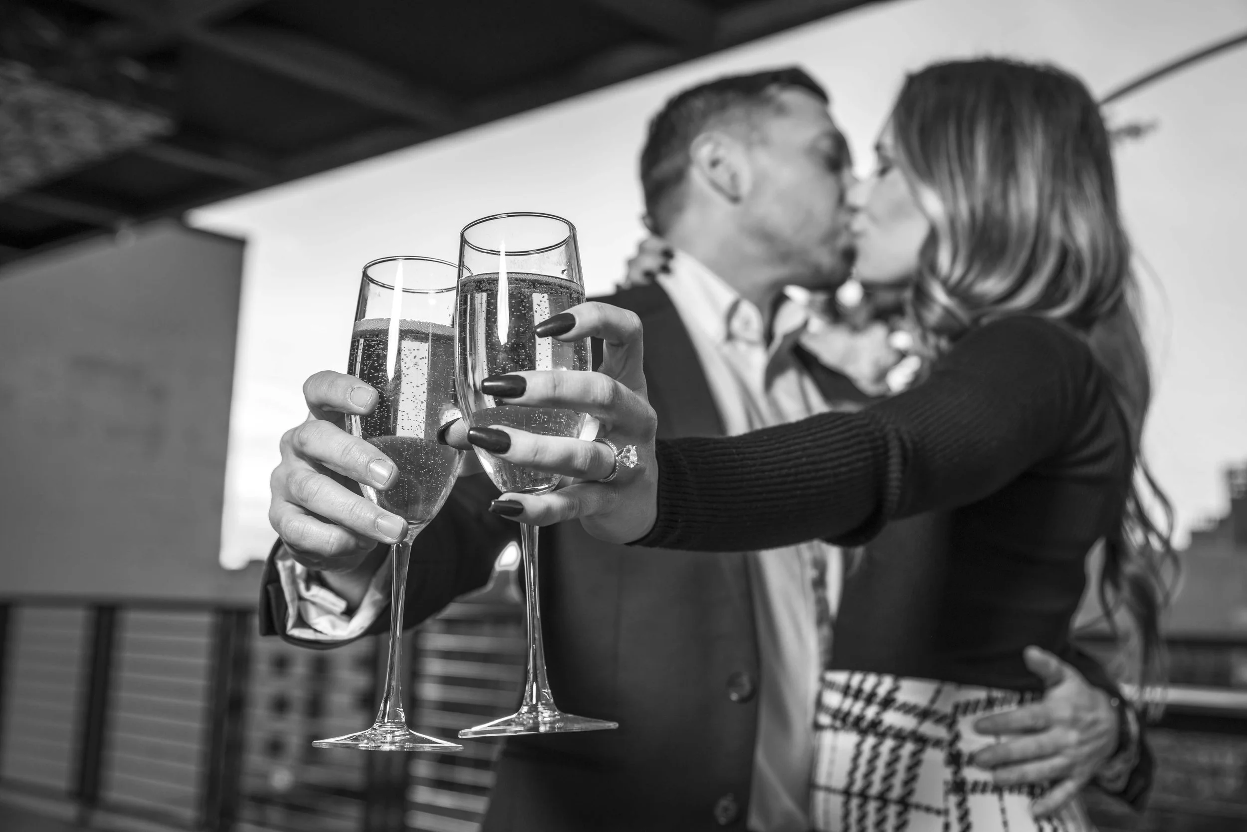 A couple kissing and holding two glasses of champagne.