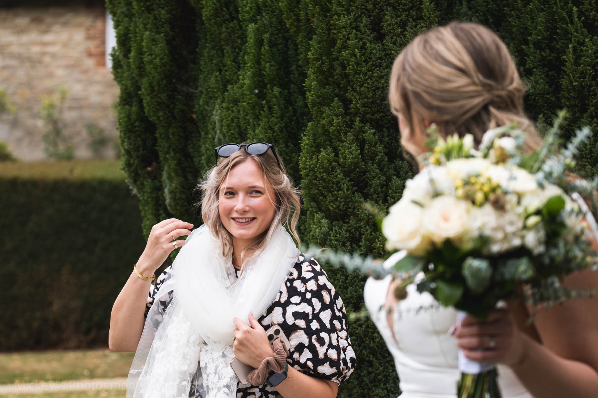 wedding-content with brides veil around her neck like a scarf, smiling at the bride