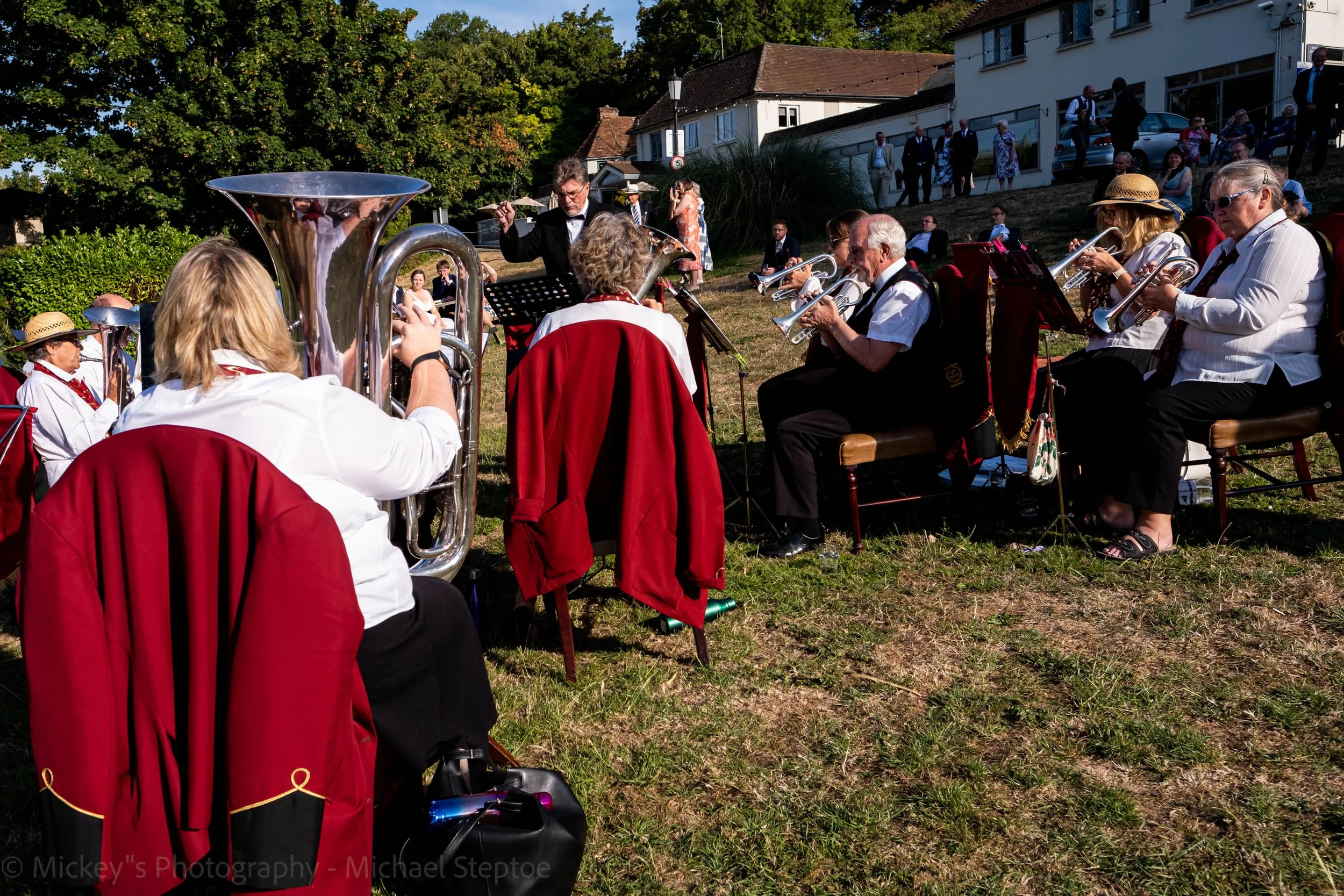 Bride and Groom and family and friends sit by the river bank outside the Shillingford bridge hotel enjoying the music that's being played by the brass band