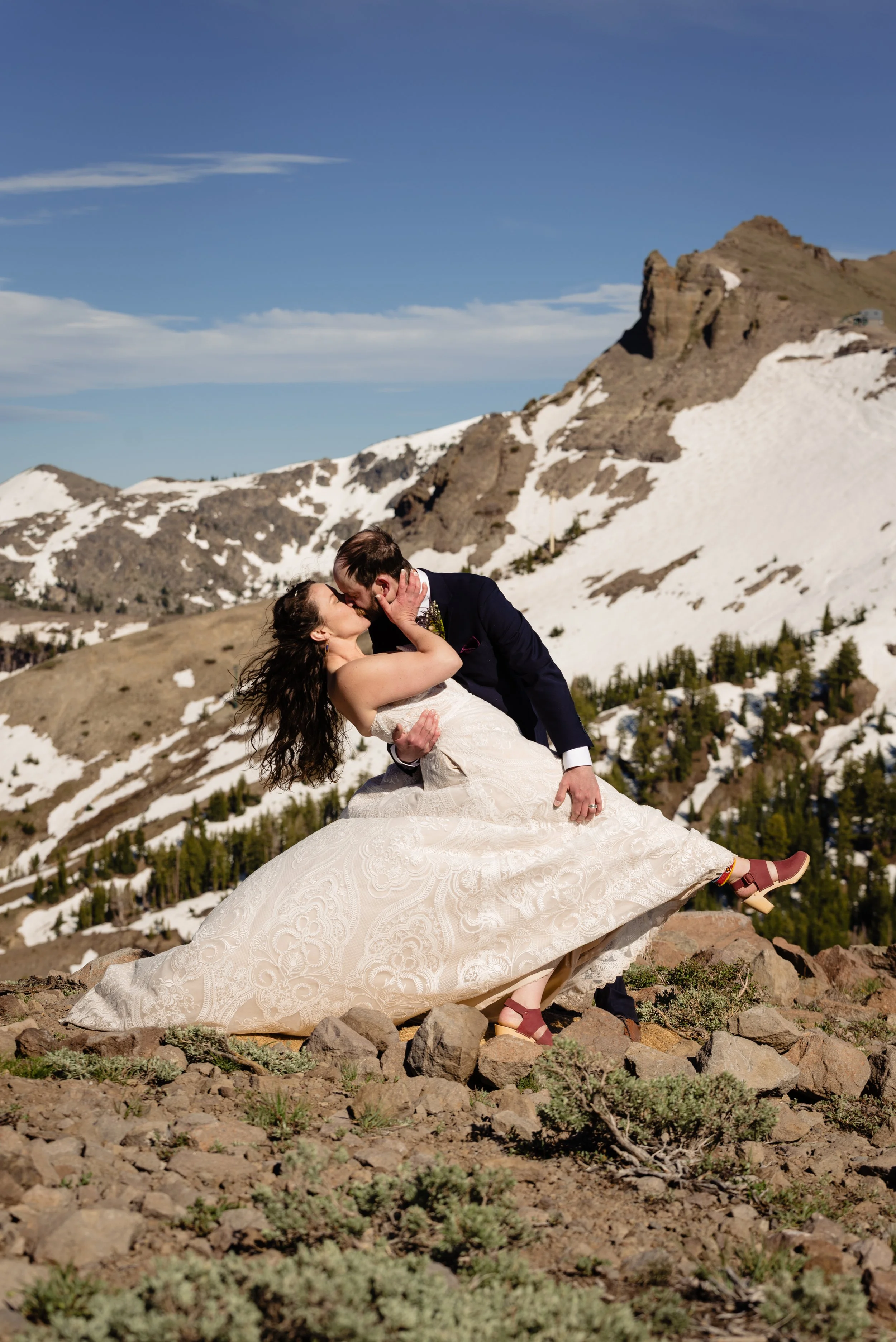  Newlyweds kissing on snow-capped mountains 