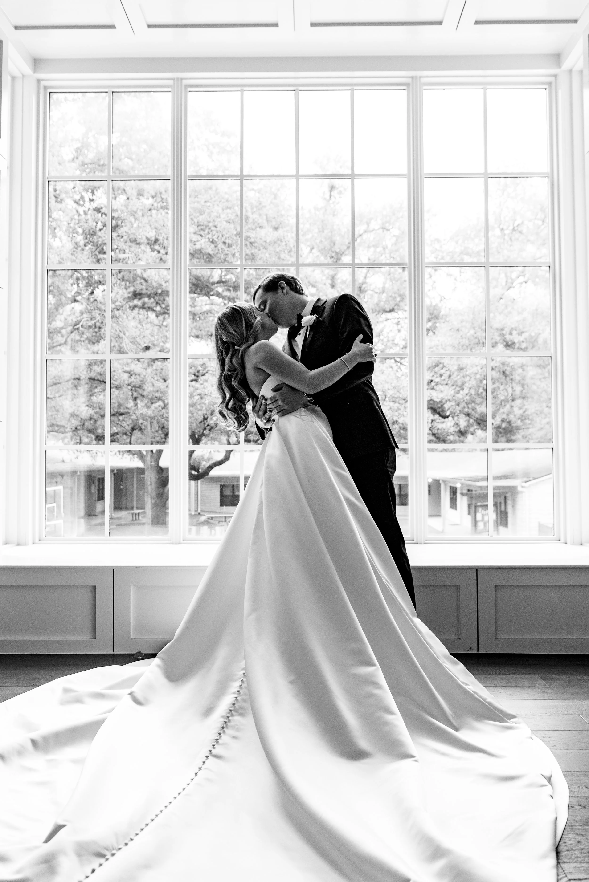 black and white image of newlywed couple in front of window