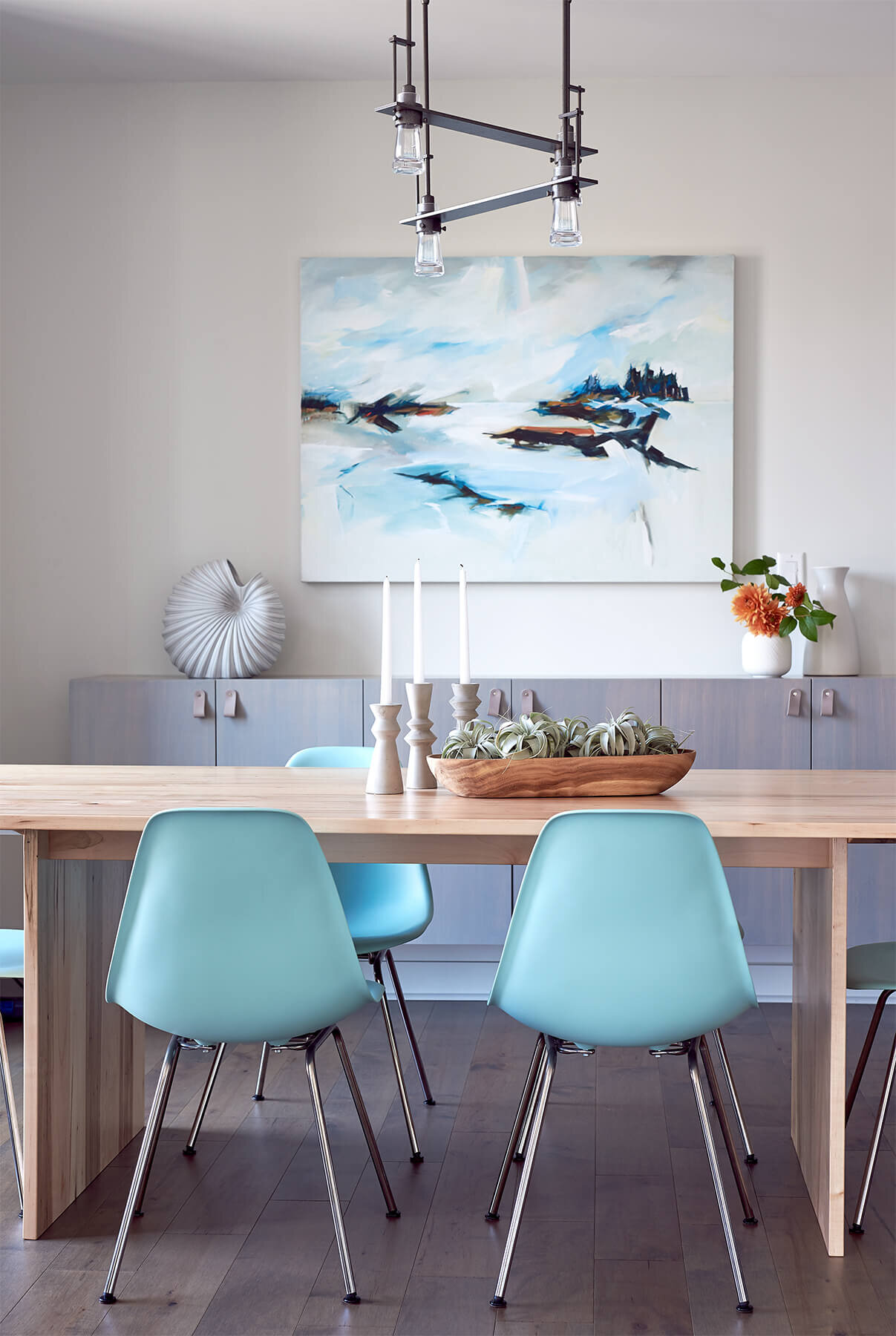 Modern Dining room with teal chairs and modern painting.