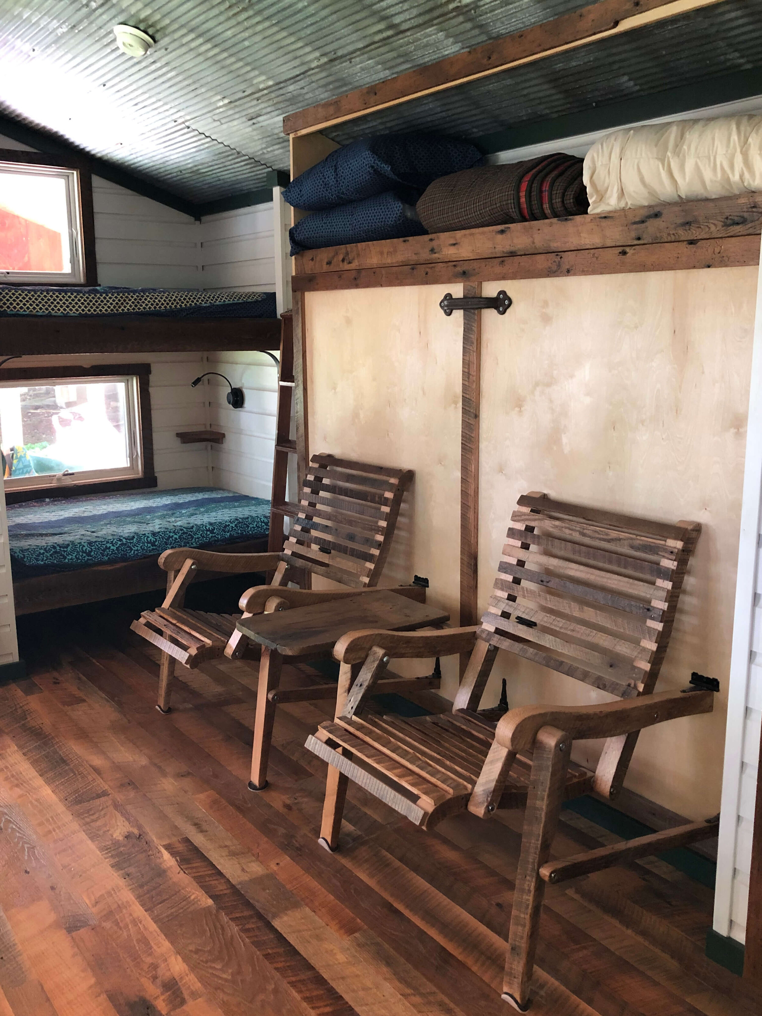  The bed in this tiny house is currently in the up position which allows two folding chairs to fold out.  