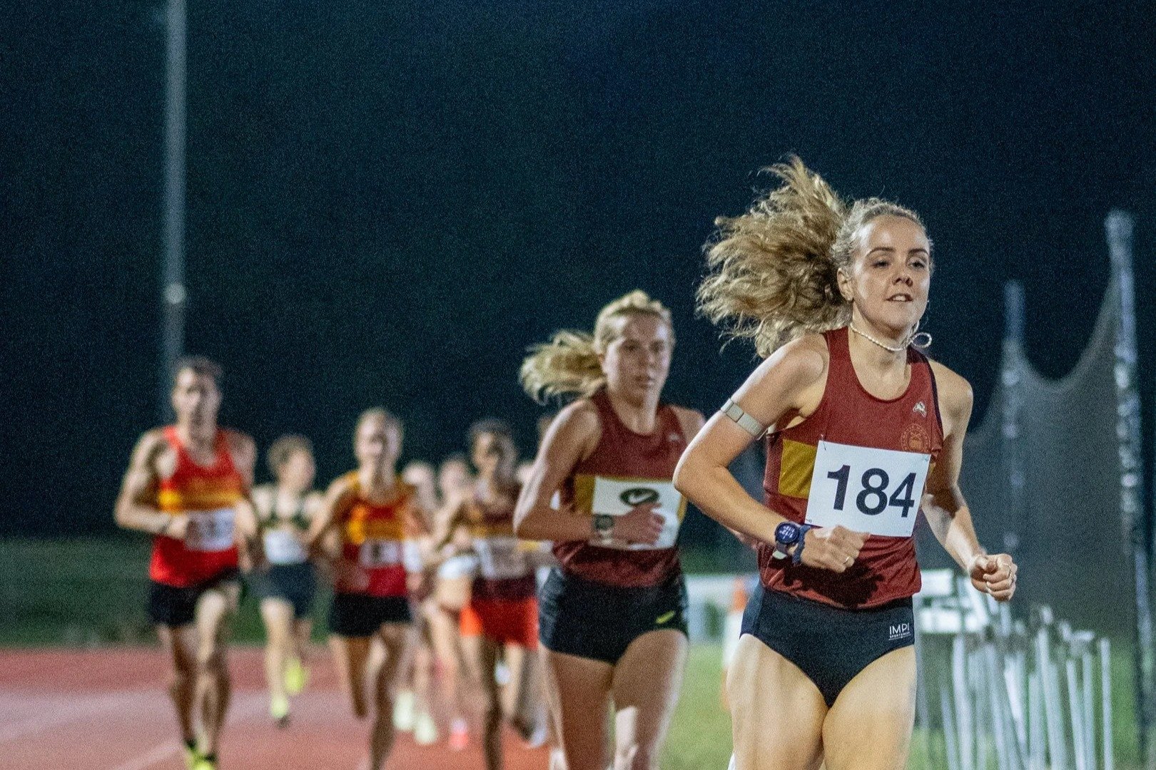 Belgrave women leading a floodlit track race during their 2025 Rosenheim League winning season