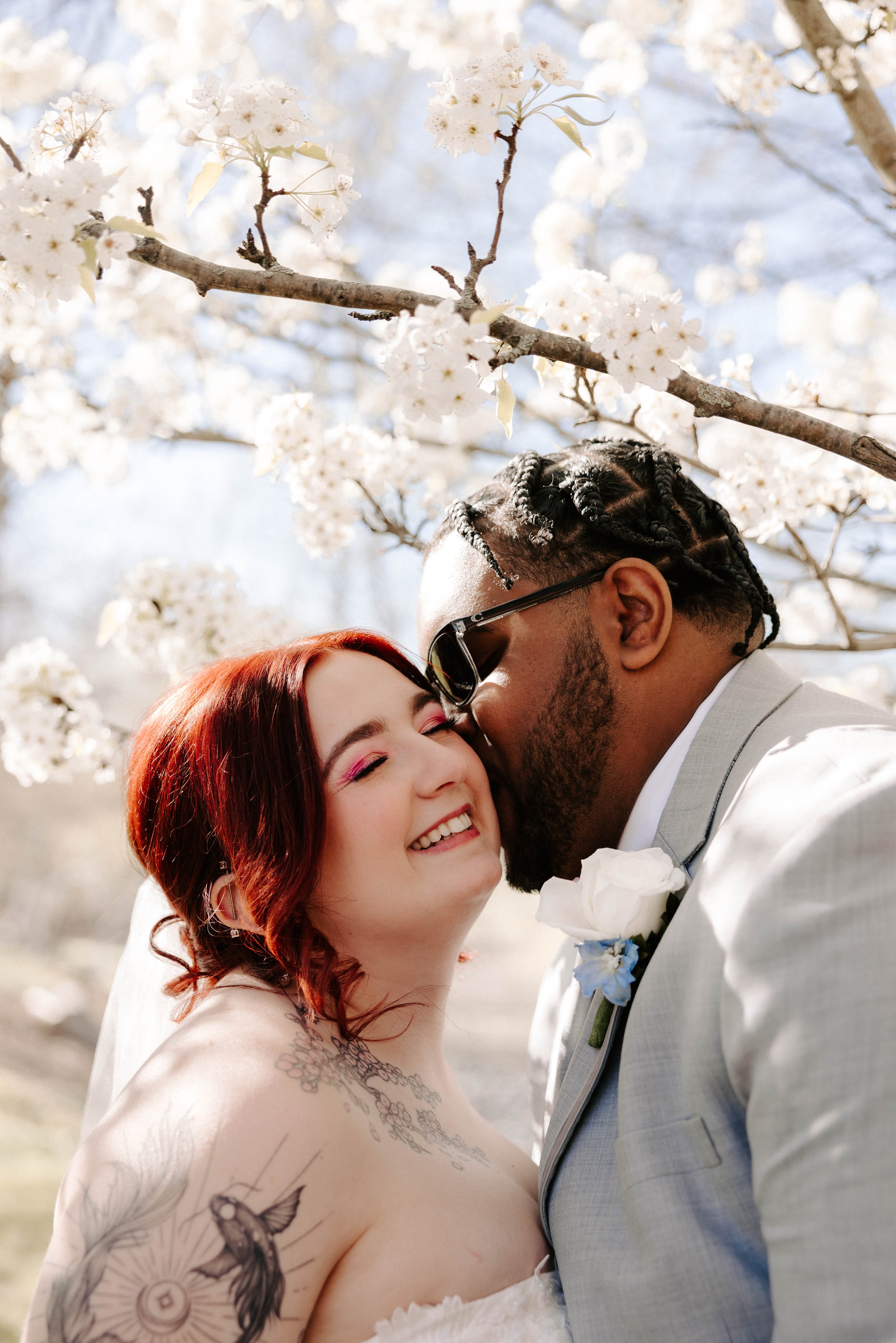 bride with fun colorful makeup getting kissed by her new groom at their wedding.