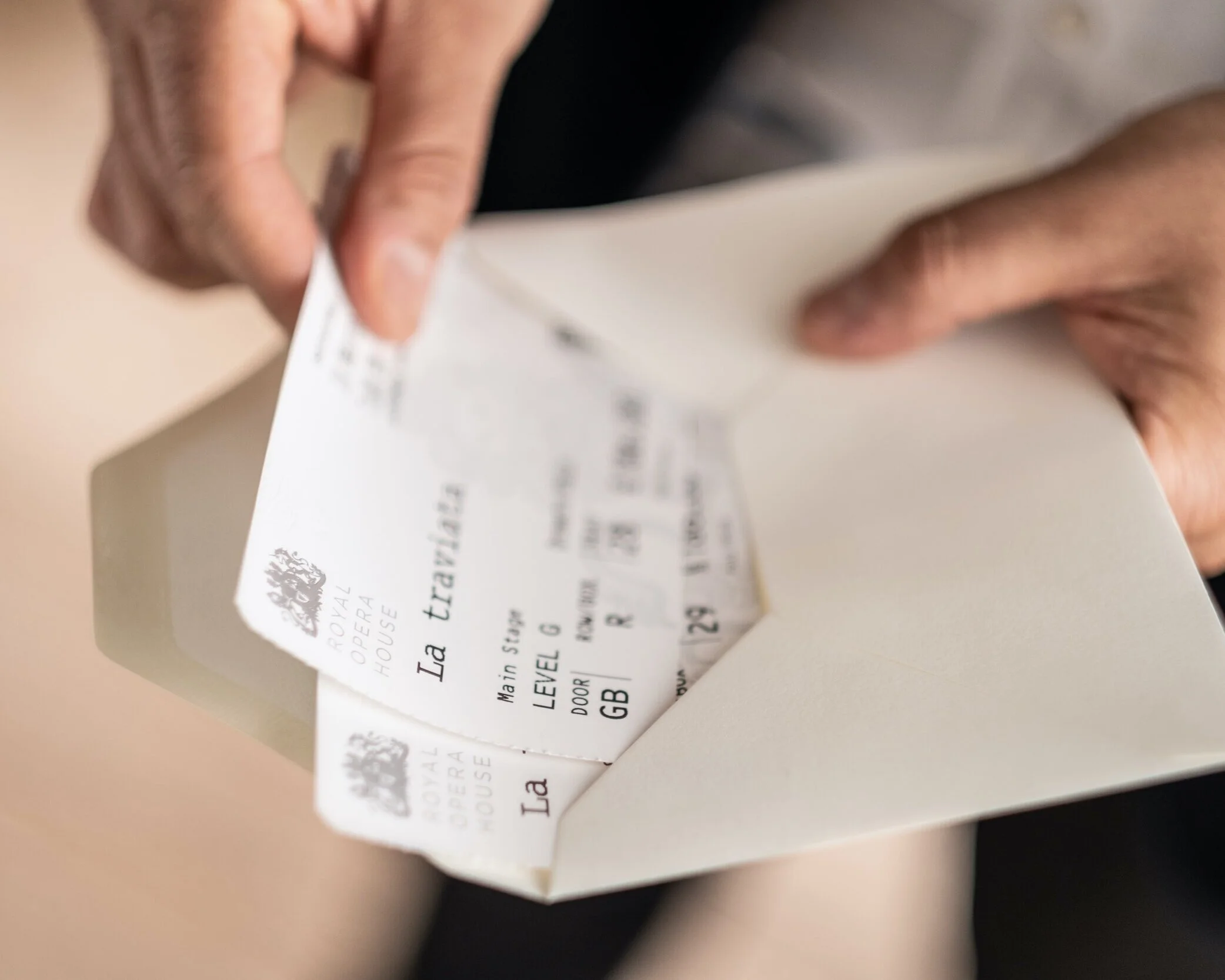 Close-up of a person's hands holding a boarding pass for a flight, with printed details partially visible.