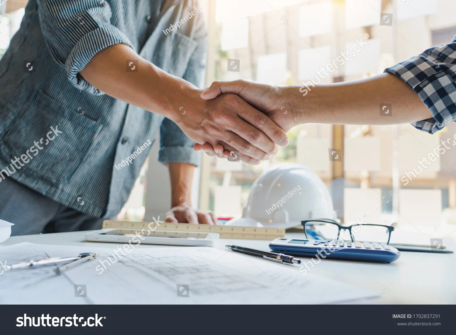 stock-photo-architect-and-engineer-construction-workers-shaking-hands-while-working-for-teamwork-and-1702837291.jpg